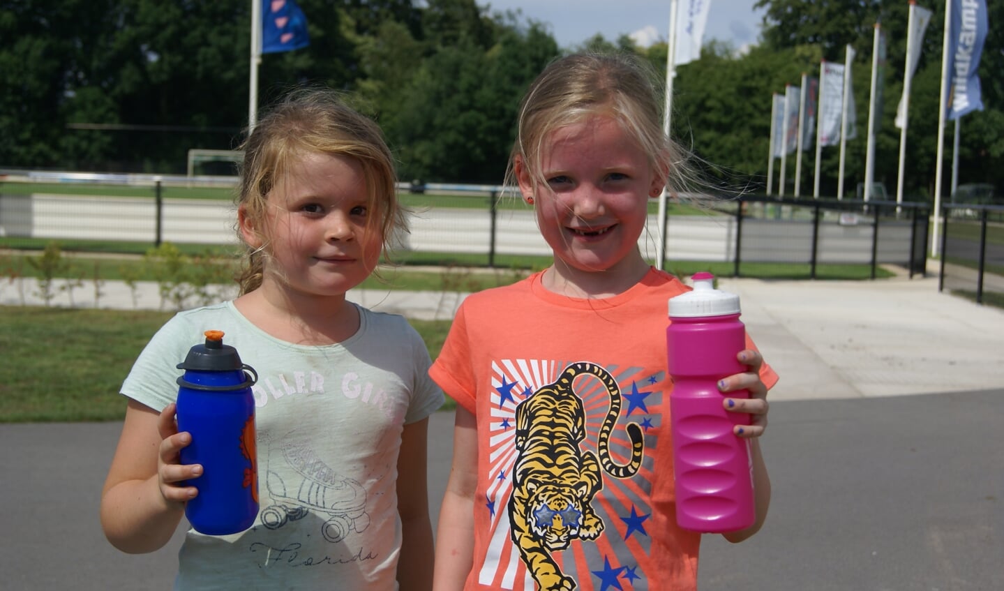 Twee meiden zijn blij dat ze drinken mee hebben, want lekker sporten maakt dorstig. Foto: Eva Schipper
