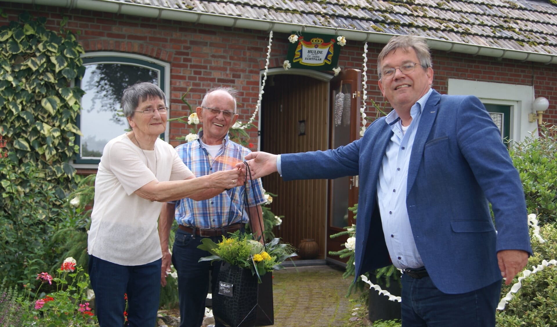 Loco-burgemeester Joop Wikkerink komt langs met een bos bloemen bij bruidspaar Te Lindert. Foto Eva Schipper