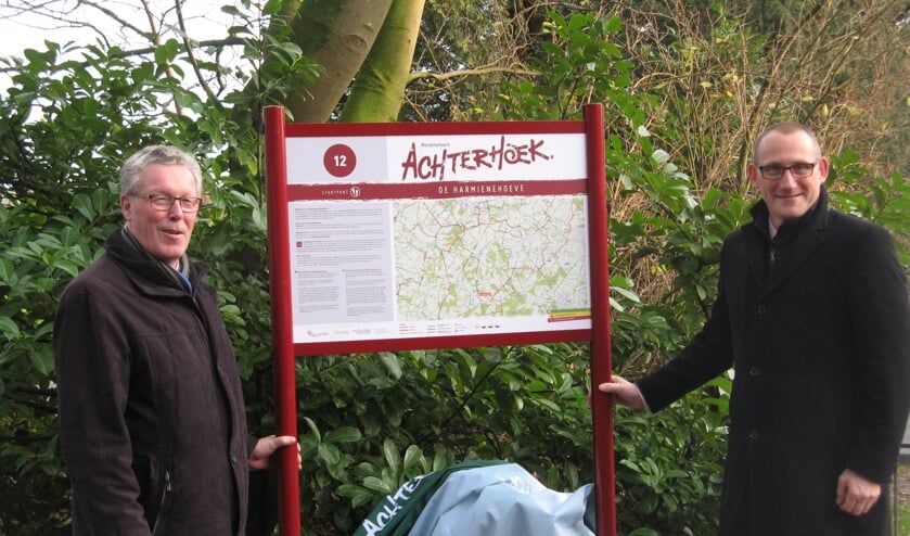 Gelders gedeputeerde Jan Markink (links) en wethouder Gert-Jan te Gronde trekken het doek van het informatiepaneel bij de Harmienehoeve, waarmee het wandelnetwerk en de digitale wandelroutes van Achterhoek Toerisme officieel in gebruik zijn genomen. Foto: Bart Kraan).