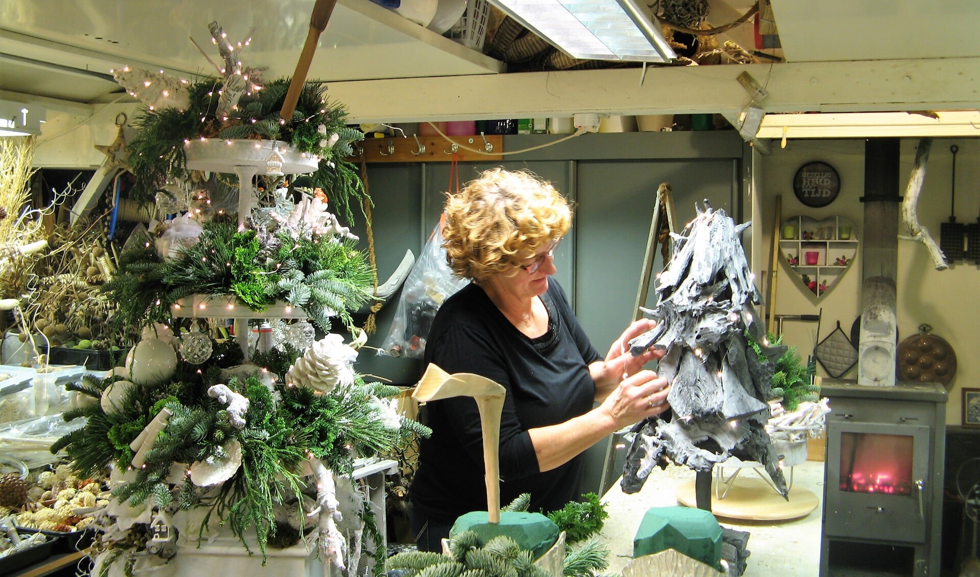 Anita Oonk aan het werk aan een kerststuk. Links de prijs voor het raadspel. Foto: Bart Kraan