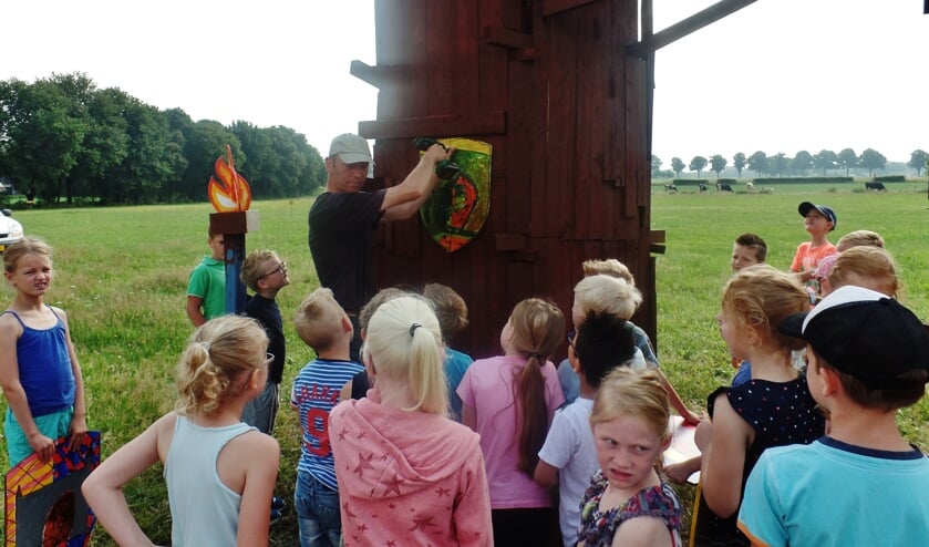 Paul Wieggers vraagt aan de kinderen of het schild op de juiste hoogte hangt.