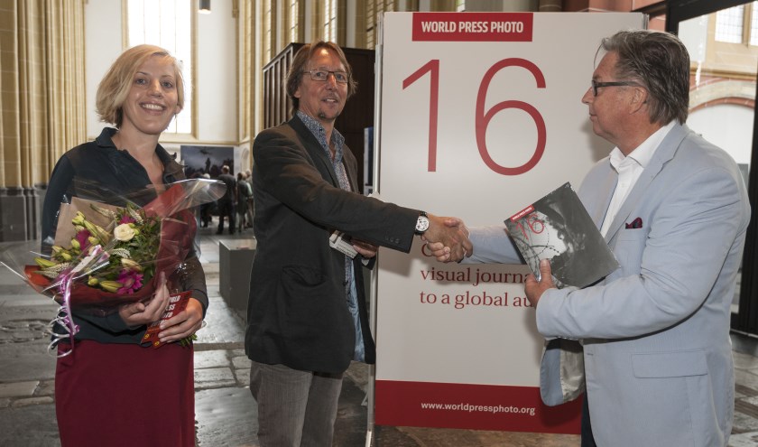 Voorzitter Peter Meulenbroek (r) overhandigt de tienduizendste bezoeker van de World Press Photo Zutphen bloemen en een fotoboek. Foto: Patrick van Gemert/Zutphens Persbureau