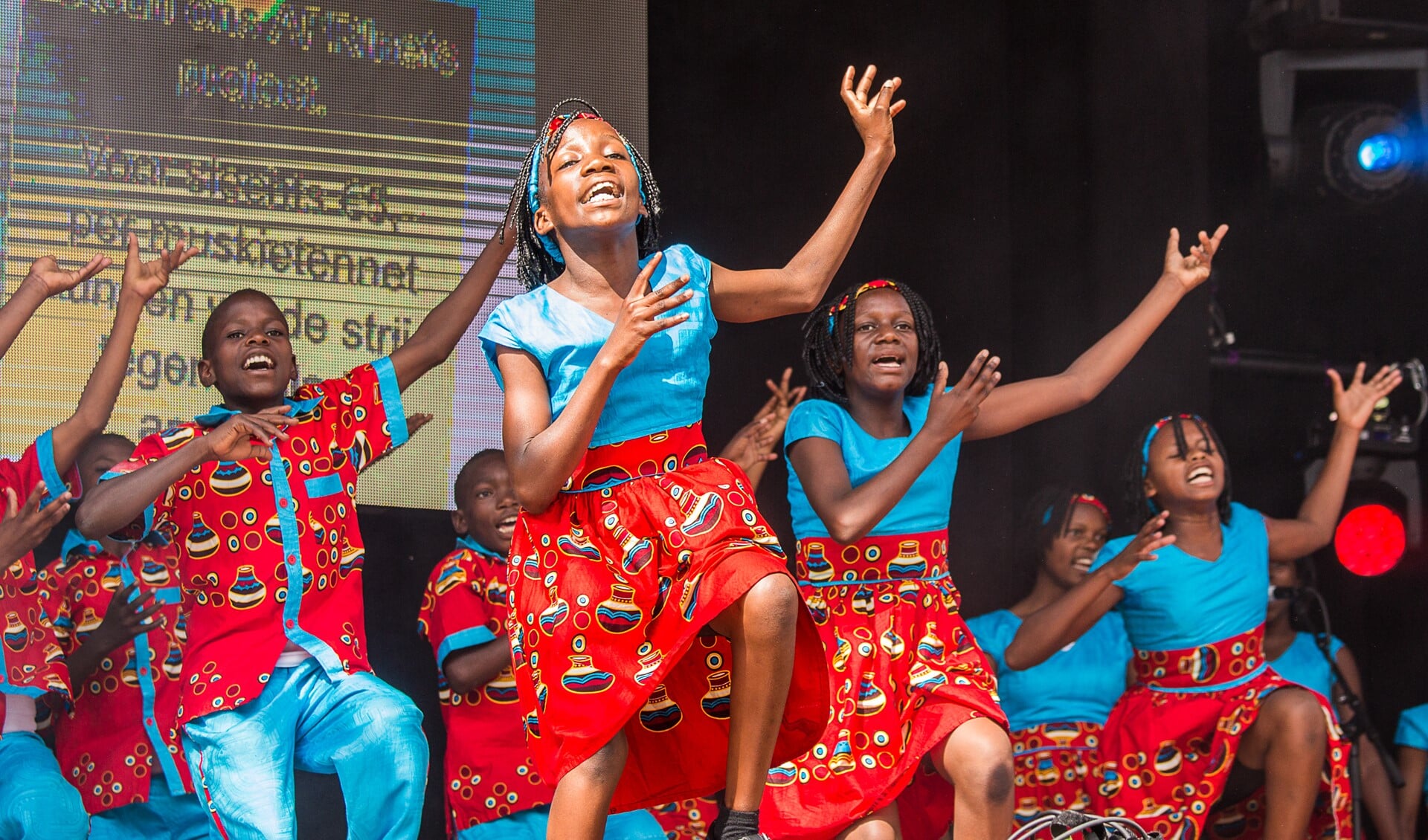Het Oegandese kinderkoor zorgt voor een kleurrijk kijk- en luisterspel. Foto: Burry van den Brink