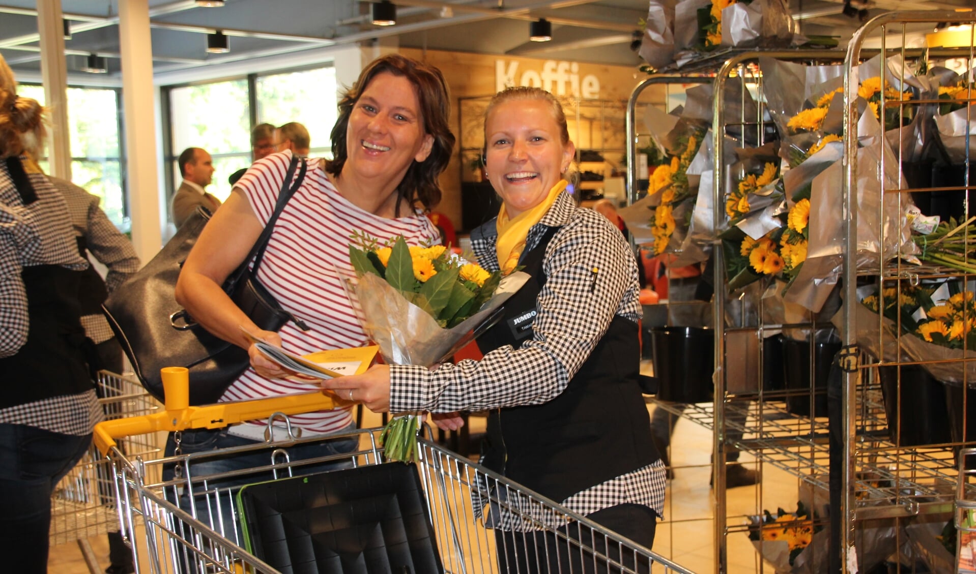 Jumbo-medewerkster Tamara geeft één van de eerste klanten een boeket bloemen en informatiemateriaal. Foto: Lydia ter Welle