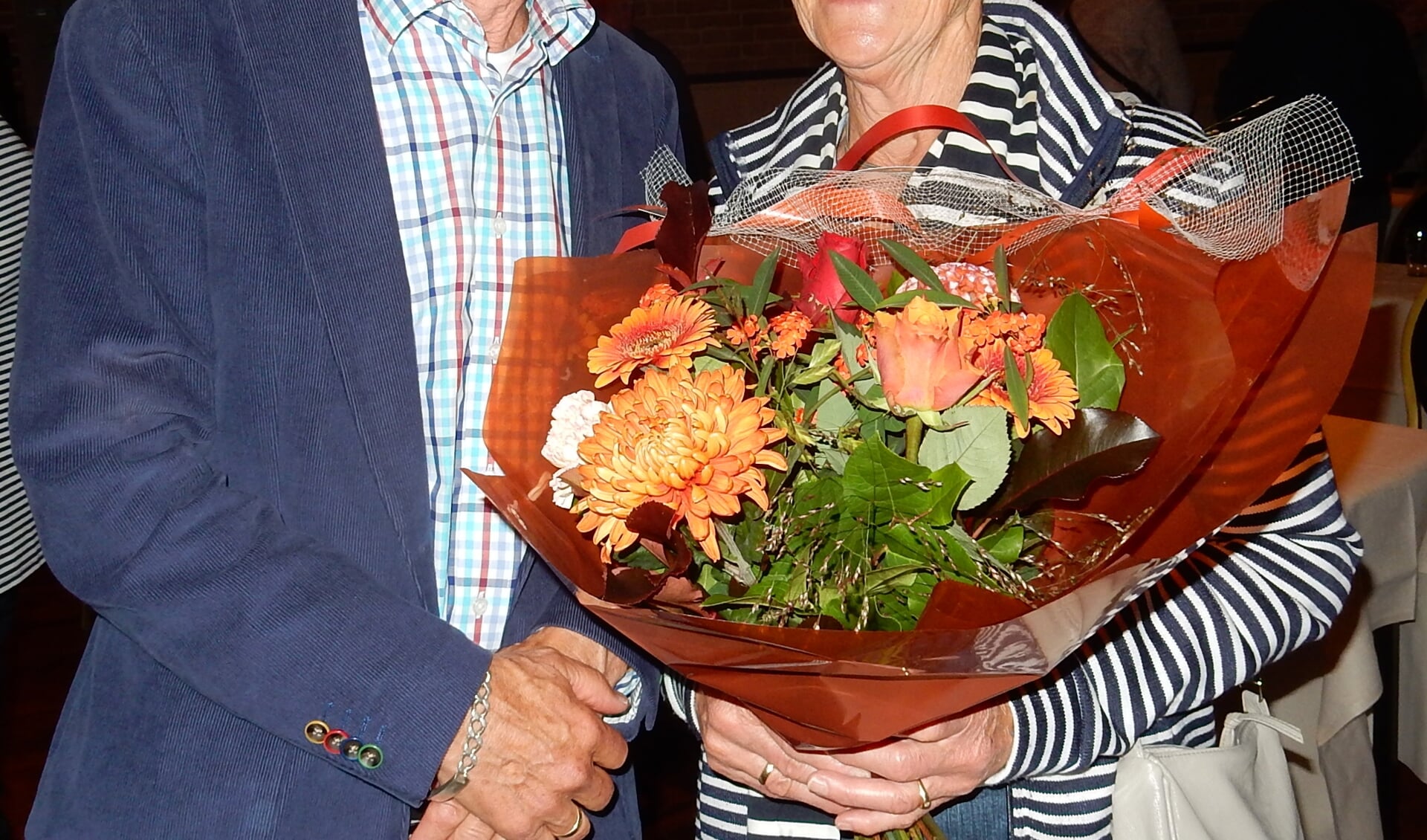 Hennie Reindsen kon om gezondheidsredenen niet aanwezig zijn, dus nam zijn vrouw Annie de bloemen in ontvangst uit handen van Wim Ruiterkamp. Foto: PR