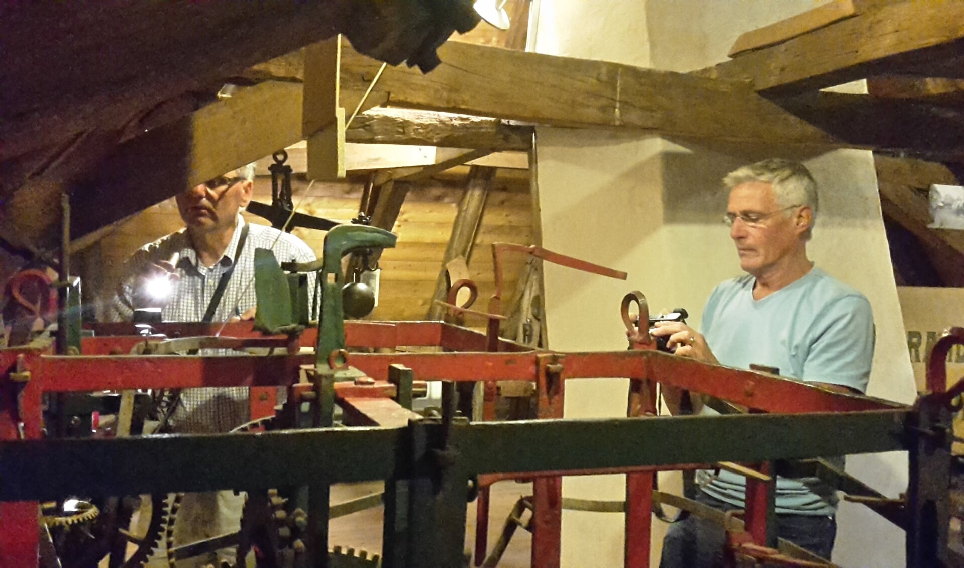 Johan Ploegaert en Bert Willems van de Stichting tot behoud van het Torenuurwerk inspecteren het uurwerk. Foto: Gemeente Aalten 