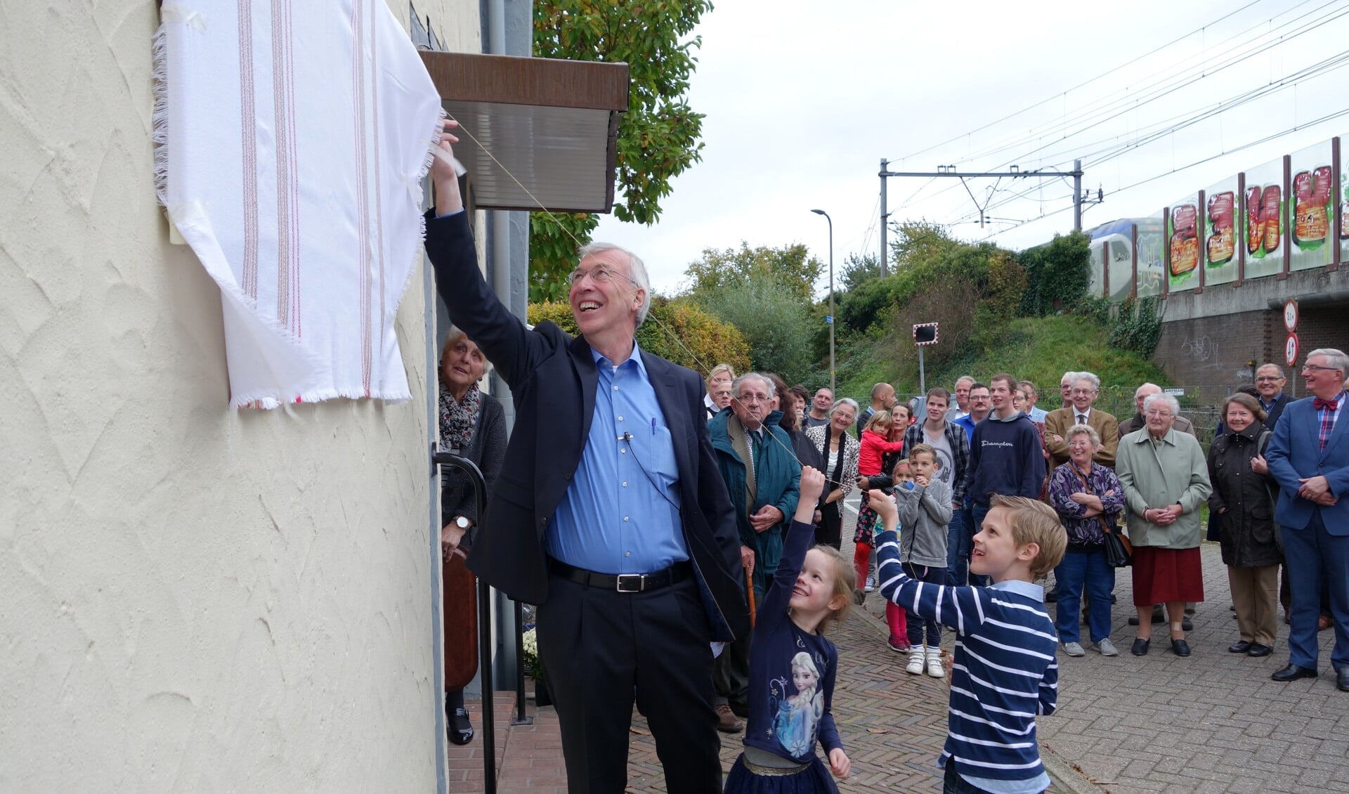 Met hulp van Jorick en Aileen onthult Gerjan Nijland het nieuwe bord van de hervormde gemeente. Foto: PR