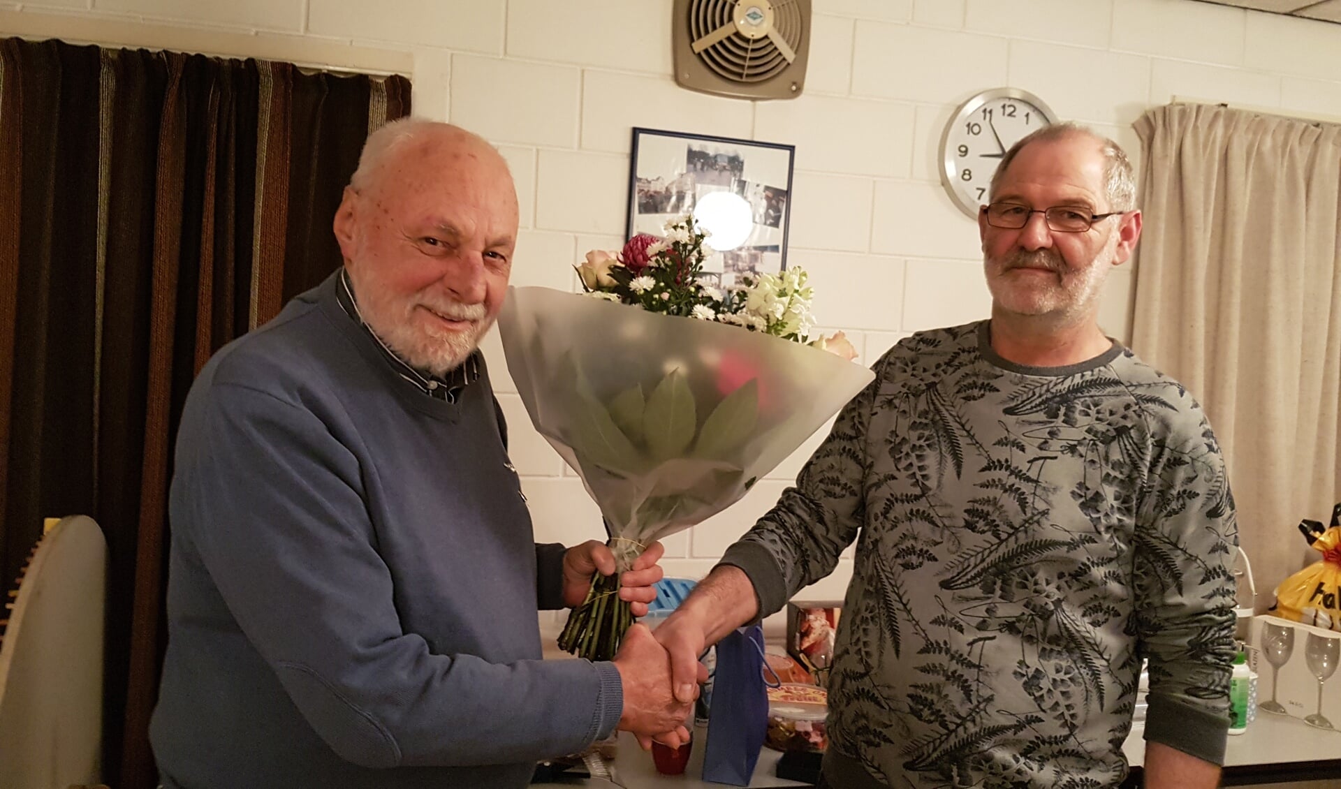 Johan Poelman (l.) kreeg van voorzitter Hans Menkhorst een zilveren speld en bloemen. Foto: PR