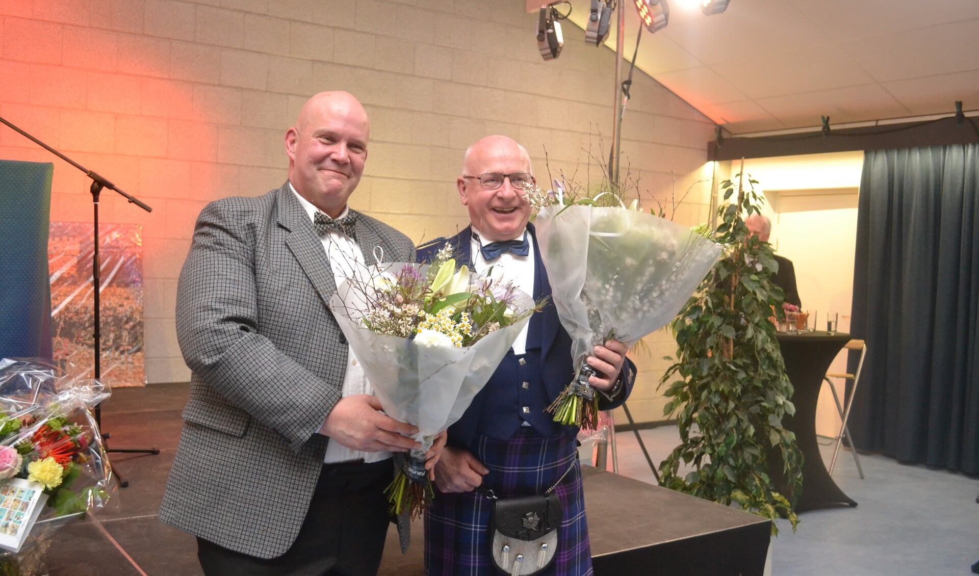 Oprichter Hans Beerten (r) en voorzitter Johan van Doesburg van de Highland Valley Pipes en Drums ontvangen bloemen tijdens het jubileum. Foto: Jaime Lebbink