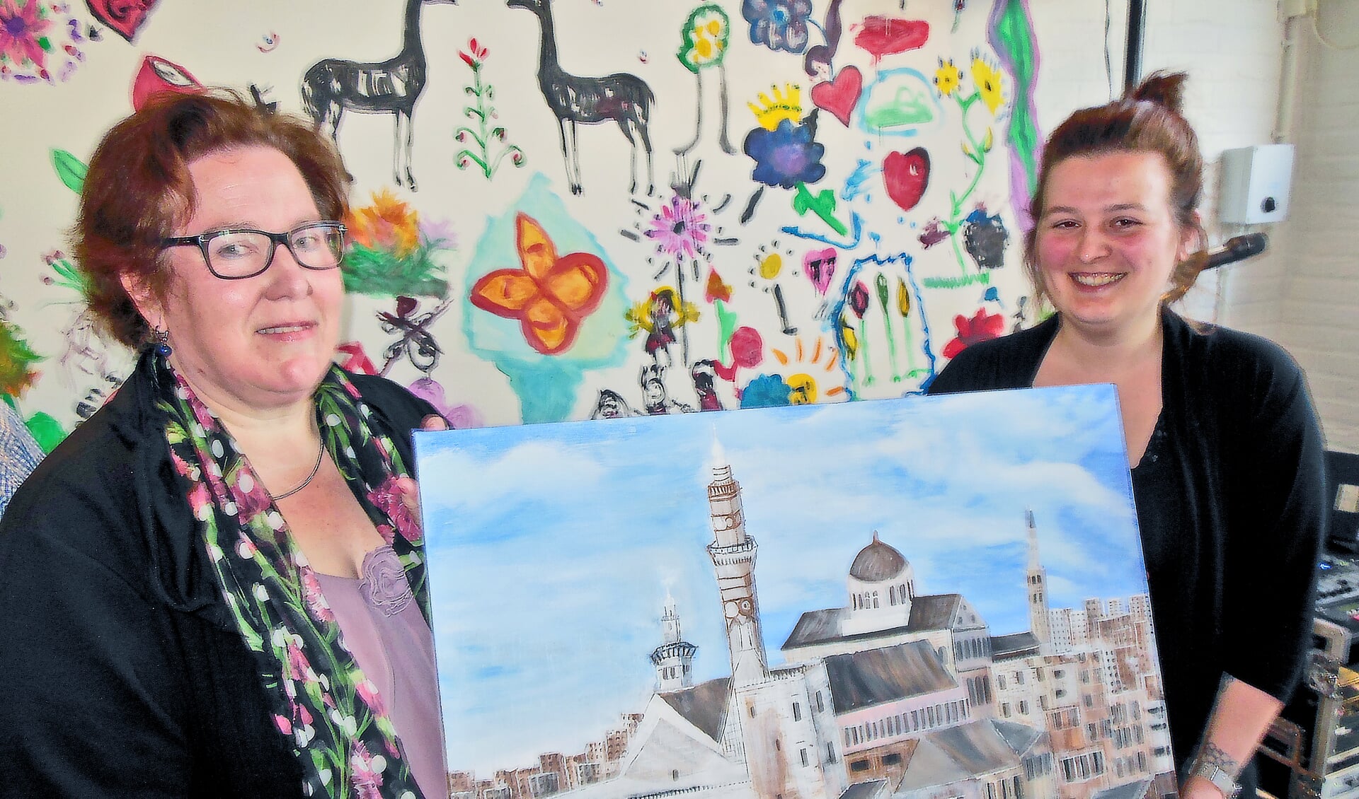Dorpsraadvoorzitter Elly Smeitink (links) en complexbeheerder Eline der Weduwen tonen het schilderij van de gevluchte kunstenaar Talal Shkeifah. Het komt in de gemeenschapsruimte te hangen. Foto: Eric Klop