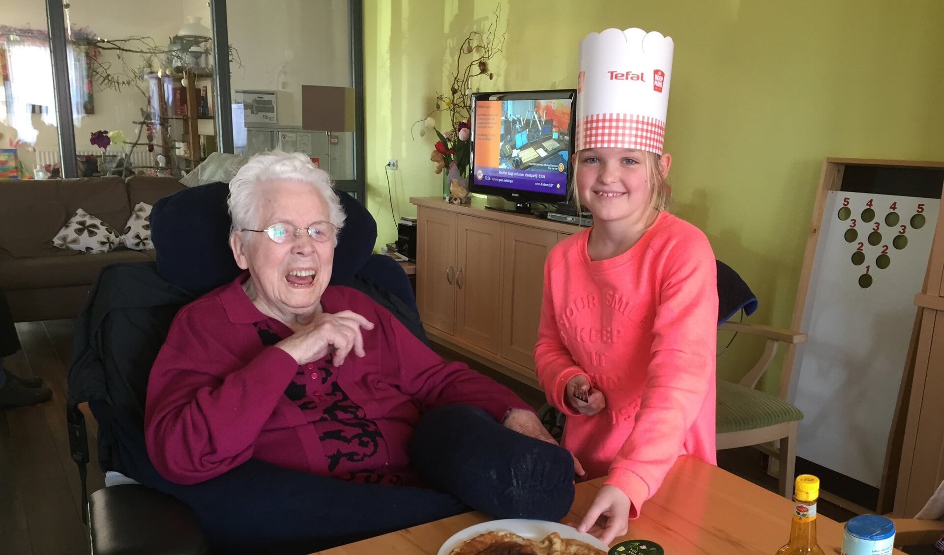 Jet Wiegerinck (10) biedt mevrouw Jantje Ooijman (96) een zelfgebakken pannenkoek aan  Foto: Peter Vorderman