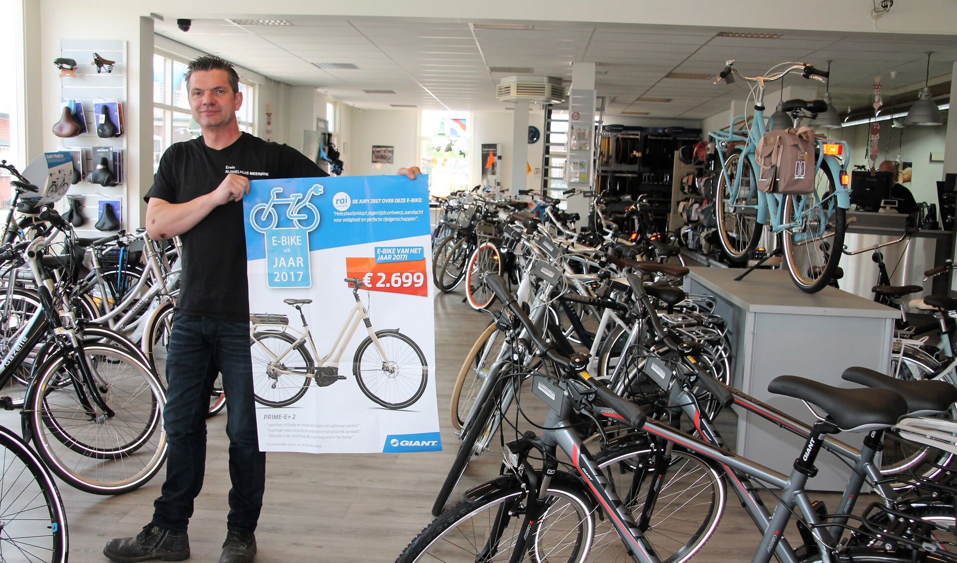 Erwin Meerdink, met een poster van de E-Bike van het Jaar, in zijn winkel aan de Wooldseweg die na Pinksteren wordt omgebouwd tot Giant Store. Foto: Lydia ter Welle