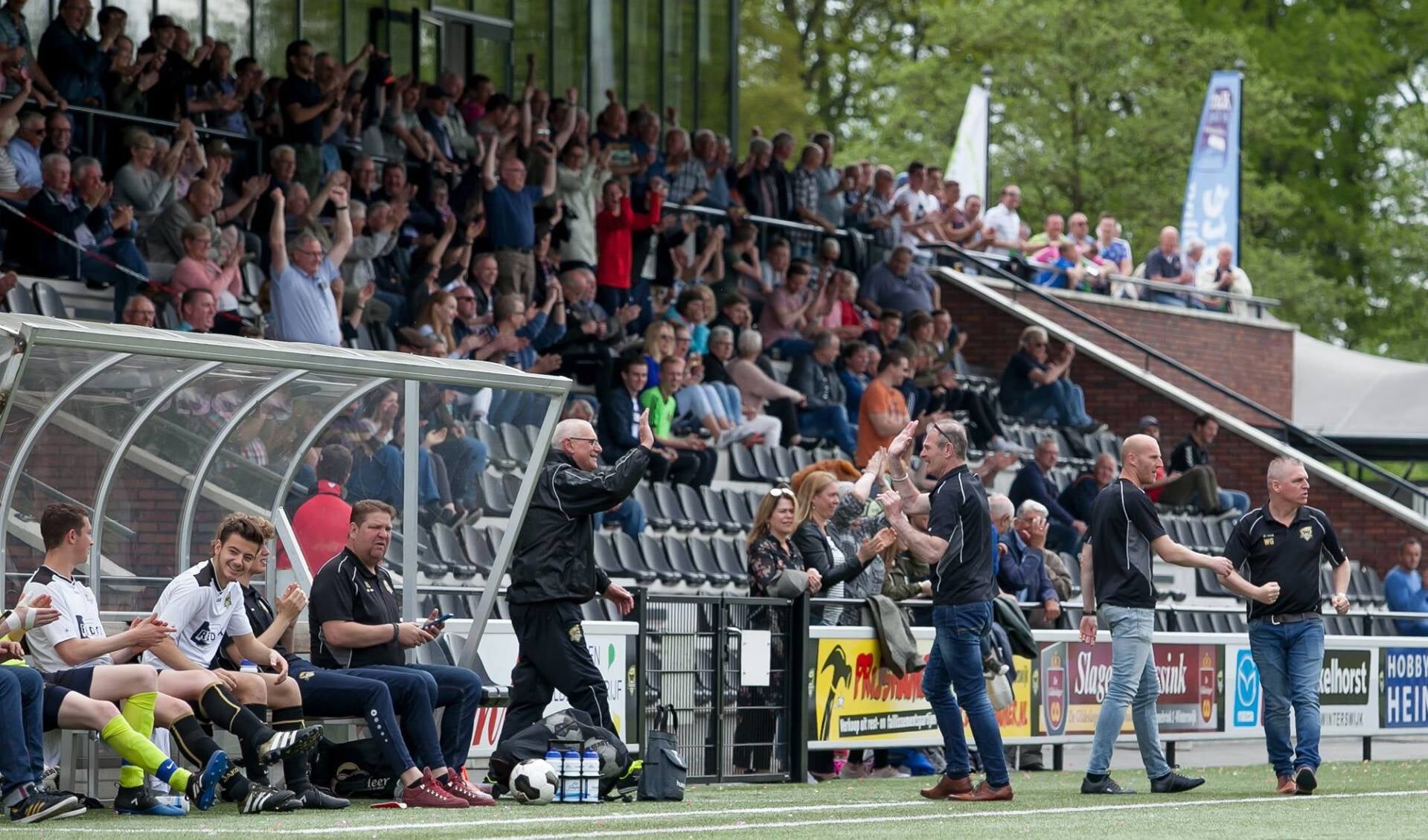 Supporters, stafleden en reserves van FC Winterswijk bejubelen een van de treffers van de  thuisclub. Foto: Marco ter Haar.