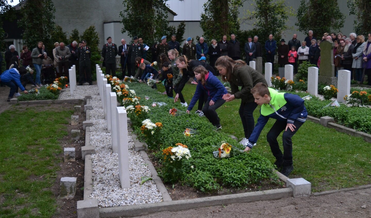 Scholieren leggen bloemen op de graven van gesneuvelde geallieerden. Foto: Karin Stronks
