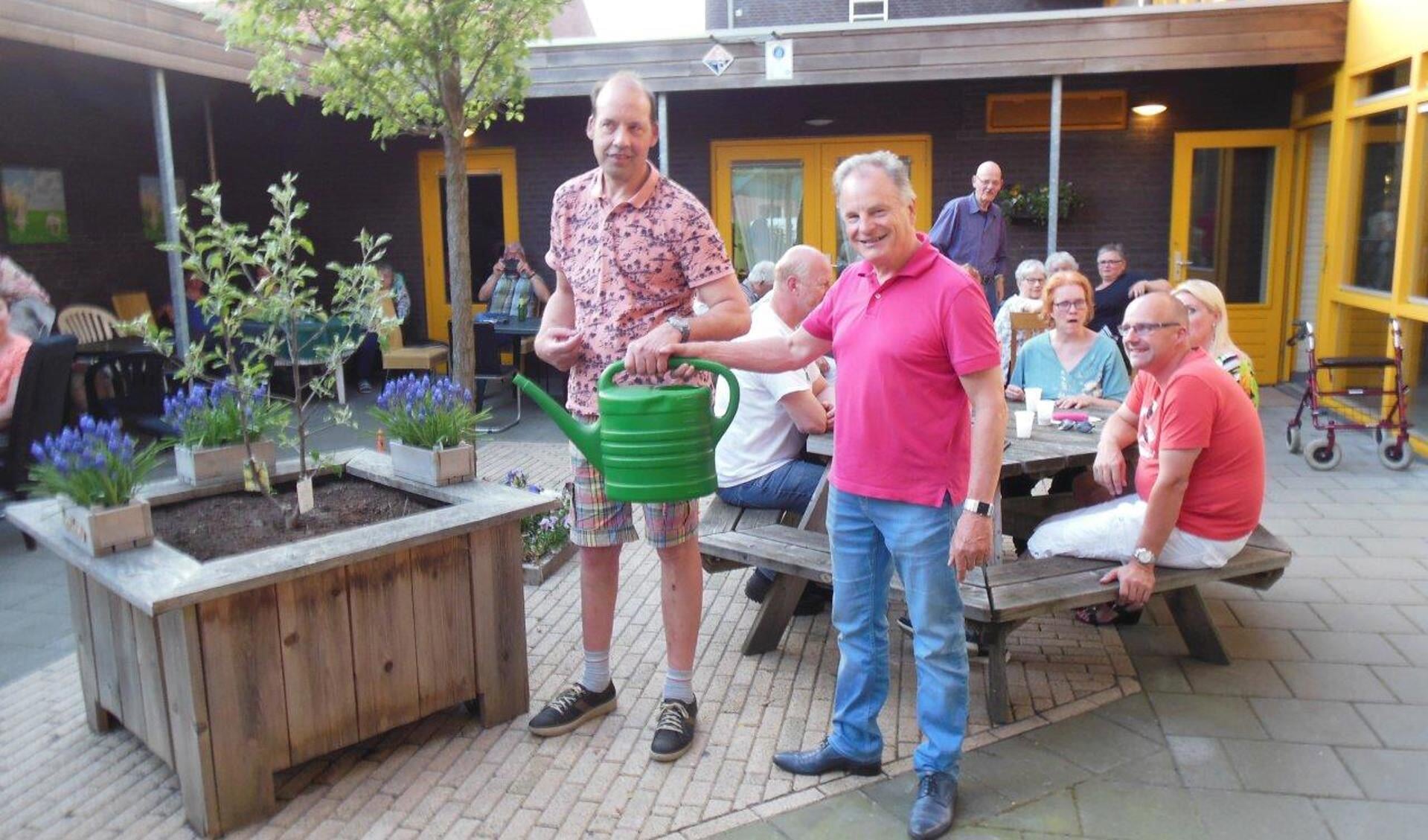 Bestuursvoorzitter Theo Verhoeven (rechts) geeft een gieter aan bewoner Henk Geessink (links) waarmee de symbolische overhandiging een feit is. Foto: PR