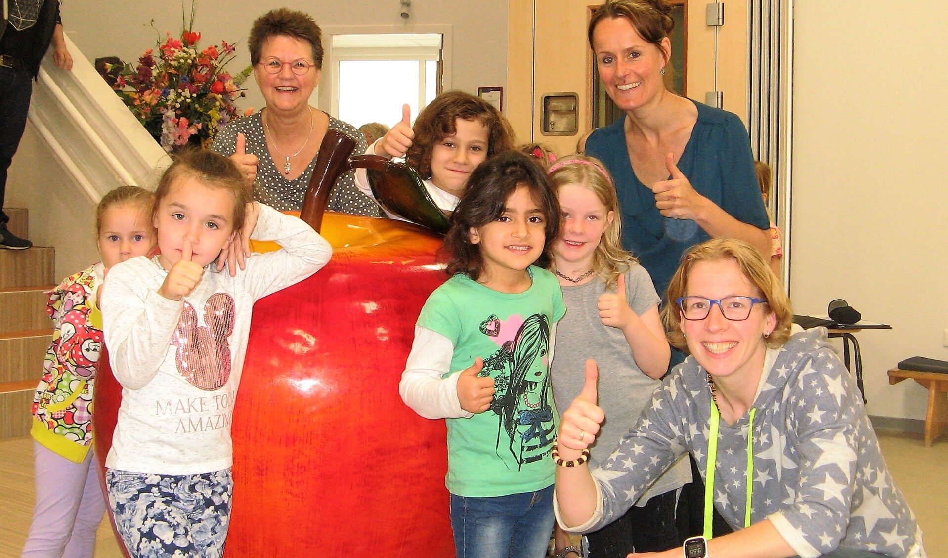 Suzan de Jong (gehurkt), Denise van der Donk (rechts), Han van Soldt en een  aantal leerlingen van De Vlier bij de grote rode appel. Foto: Bart Kraan