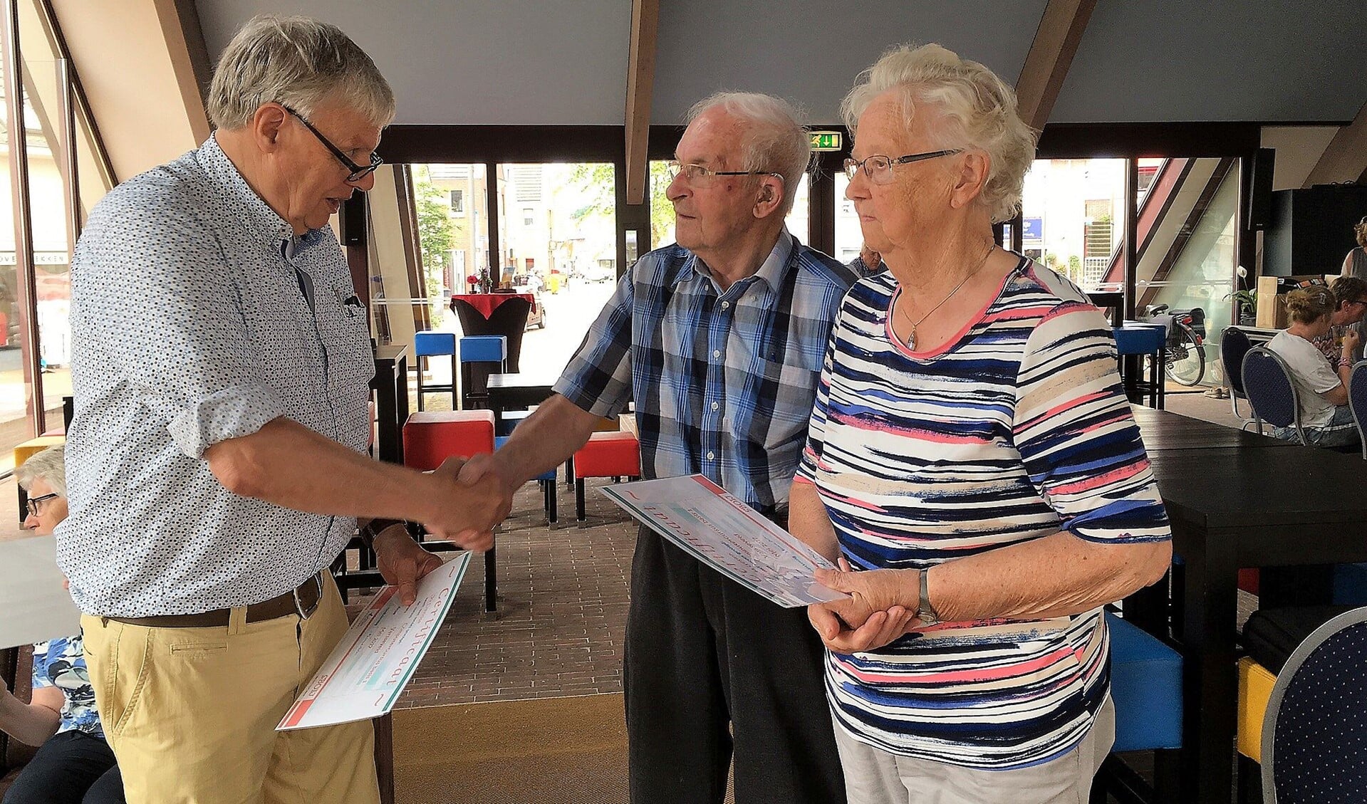 Coördinator Gerard Wesseling reikt het certificaat uit aan de 85-plussers mevrouw Gesink en de haar Davids. Foto: PR