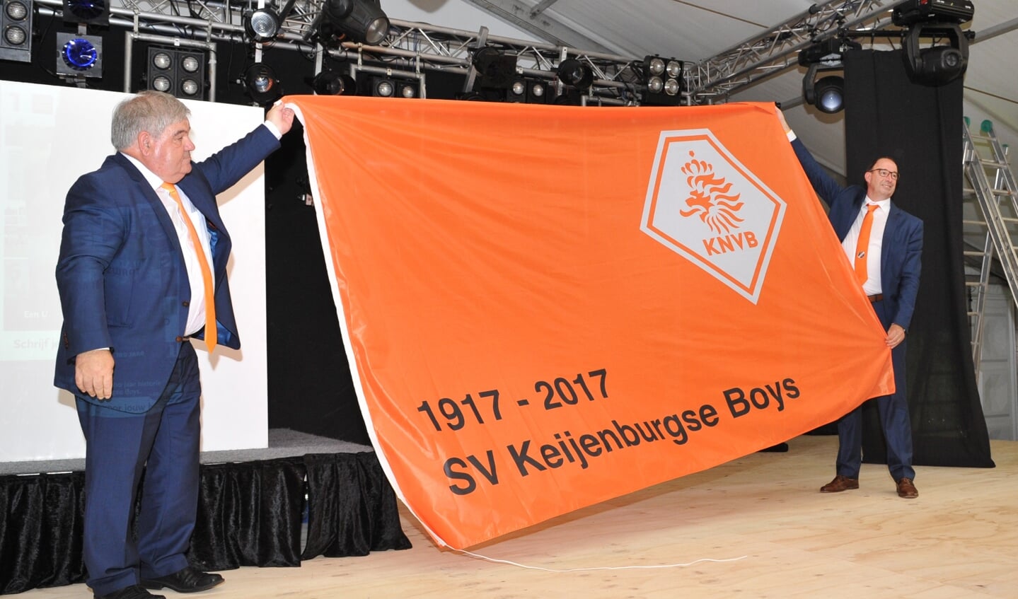 Keijenburgse Boys krijgt uit handen van KNVB-ambassadeur Gerard van Balveren een enorme oranje vlag met daarop het logo van de Nederlandse voetbalbond en de tekst ‘Keijenburgse Boys 1917-2017’. Foto: Achterhoekfoto.nl/John Mokkink