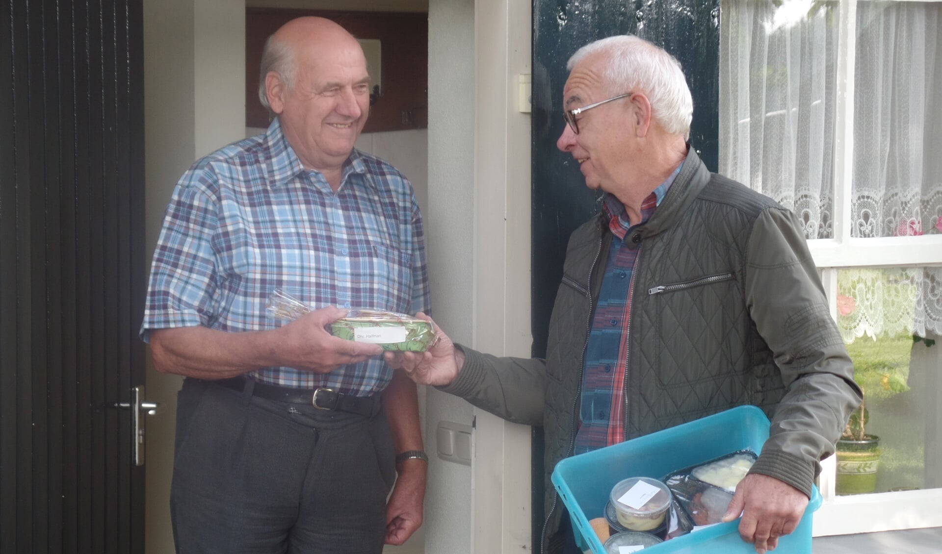 Hendrik Jan Halfman (l) neemt het geschenk en het eten van vrijwilliger Herman Dimmendaal van Tafeltje Dekje in ontvangst. Foto: Jan Hendriksen. 