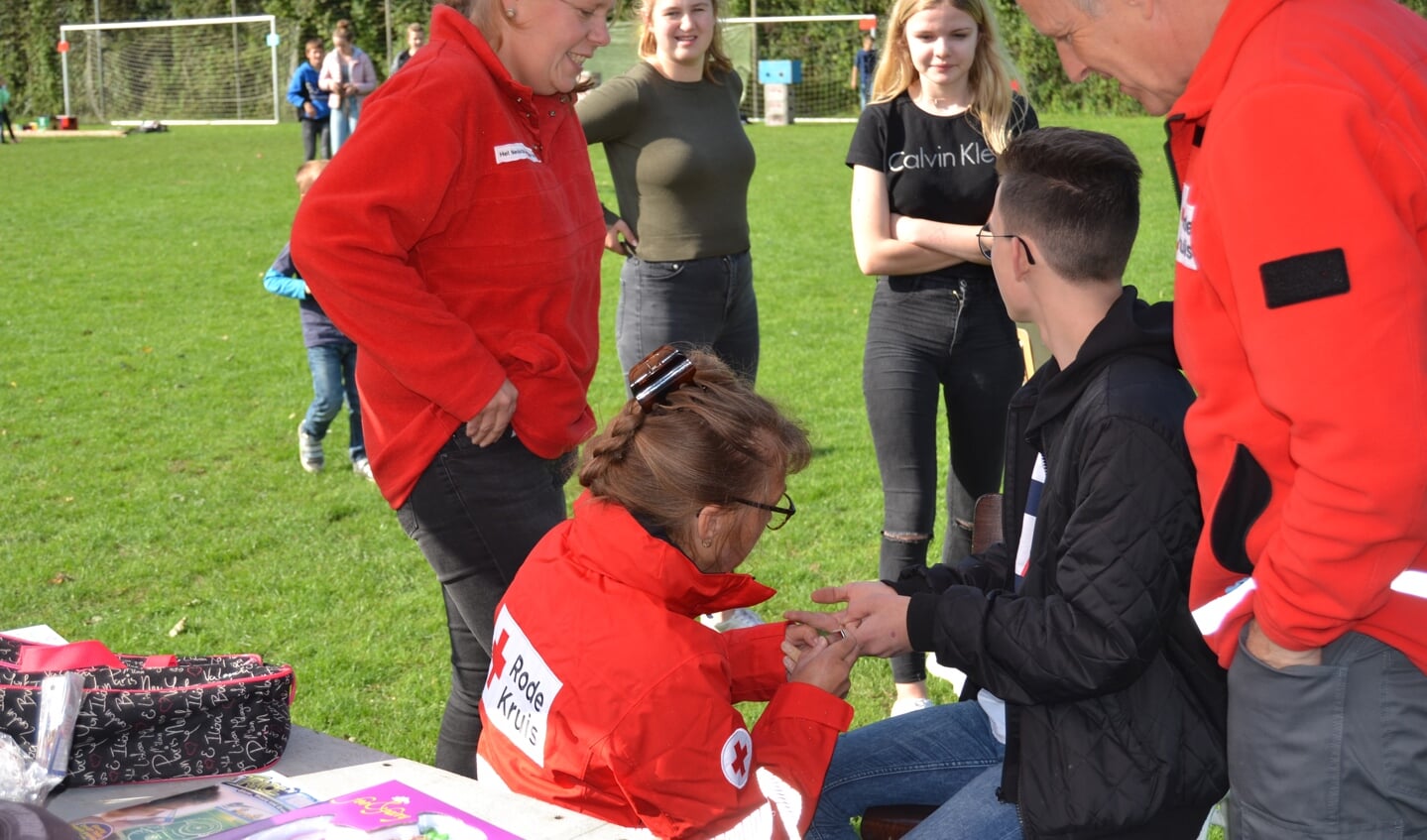 Rode Kruis medewerkers verzorgen een wond op een voetbalveld. Foto: Karin Stronks