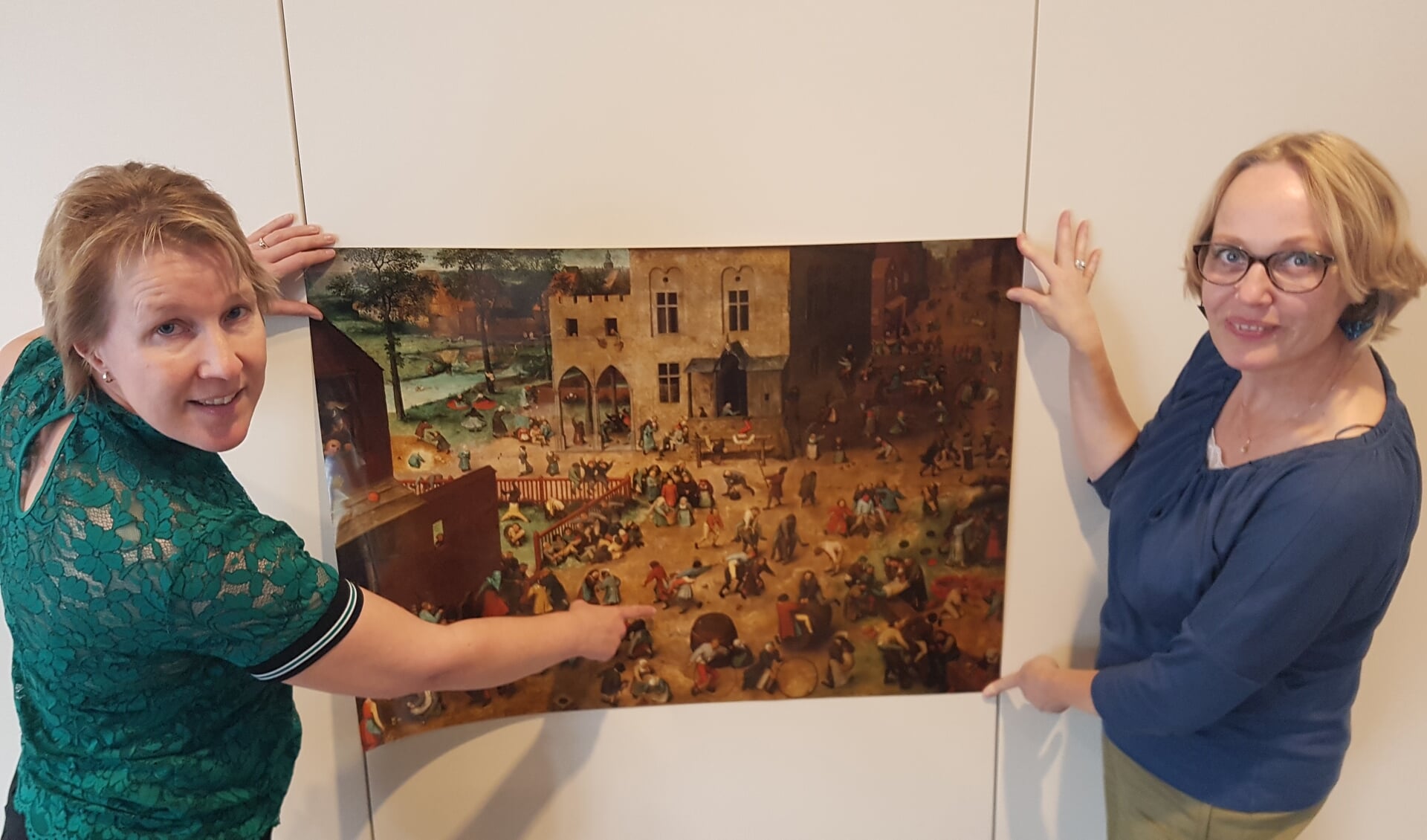 Marjolein Houwer (l) en Karin Reumer met de afbeelding 'De kinderspelen' van Bruegel, mogelijke inspiratiebron voor de (nieuwe)binnenstadgroepen. Foto: Kyra Broshuis