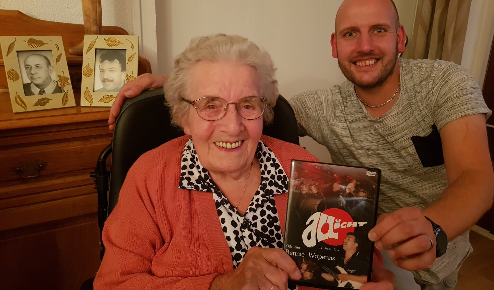 Bjorn Wopereis overhandigt zijn oma de eerste dvd van de ode aan haar zoon, op een foto achter haar staand, naast haar overleden man. Foto: Henri Walterbos 