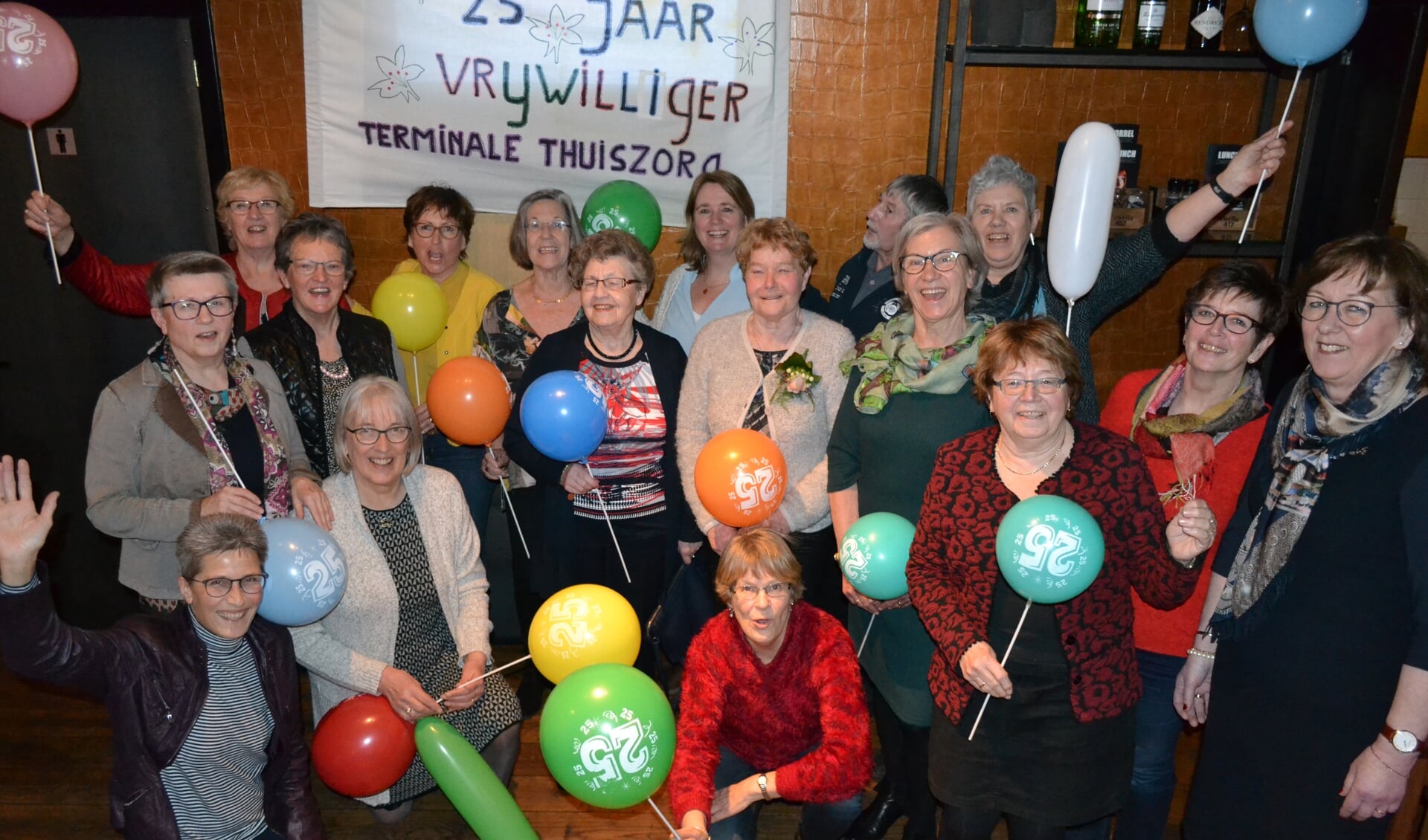 Agnes Berendsen (oranje ballon en bloemencorsage) te midden van het team vrijwilligers van Hospicegroep de Lelie. Geheel rechts: Joke Verwey. Foto: Leander Grooten