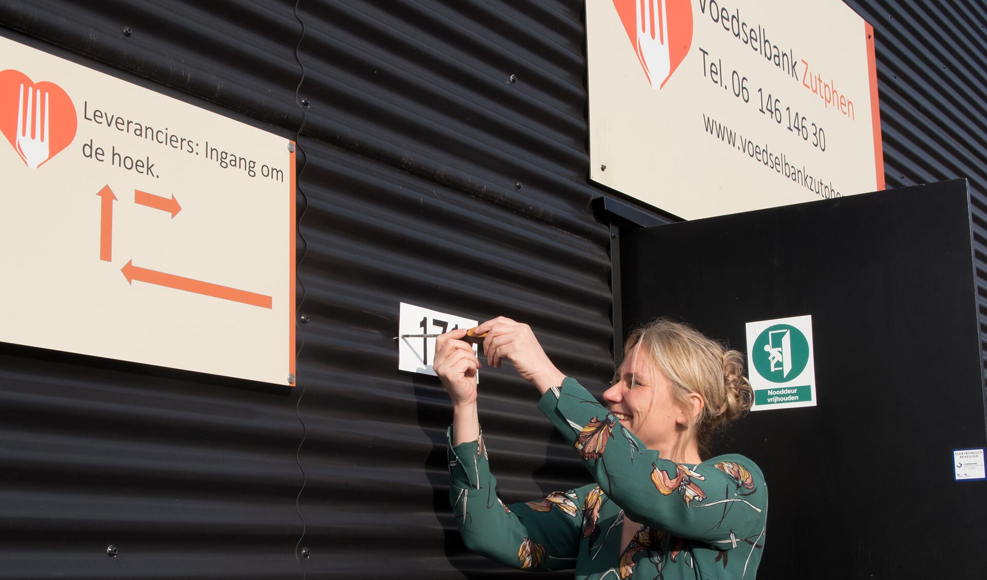 Annelies de Jonge schroeft het nieuwe huisnummer op het pand van de voedselbank. Foto: PR