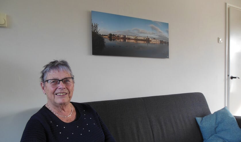 Alie Beker-Beumer onder een ingelijste foto waarop onder meer haar ouderlijk huis prijkt. “Mijn vader en moeder stelden hun leven in de waagschaal.” Foto: Eric Klop