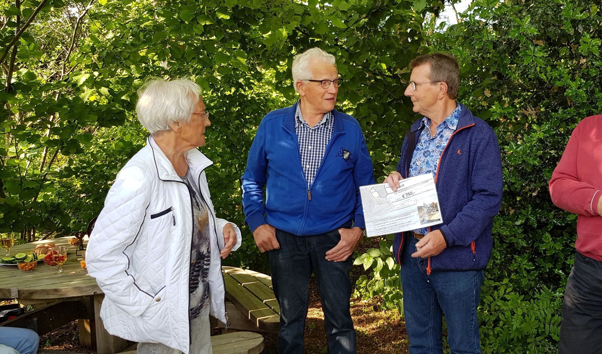 Jan Berendsen met de cheque die Fien Rouwhorst (links) hem in naam van haar man overhandigd  heeft. Midden: Harry te Molder. Foto: Alice Rouwhorst