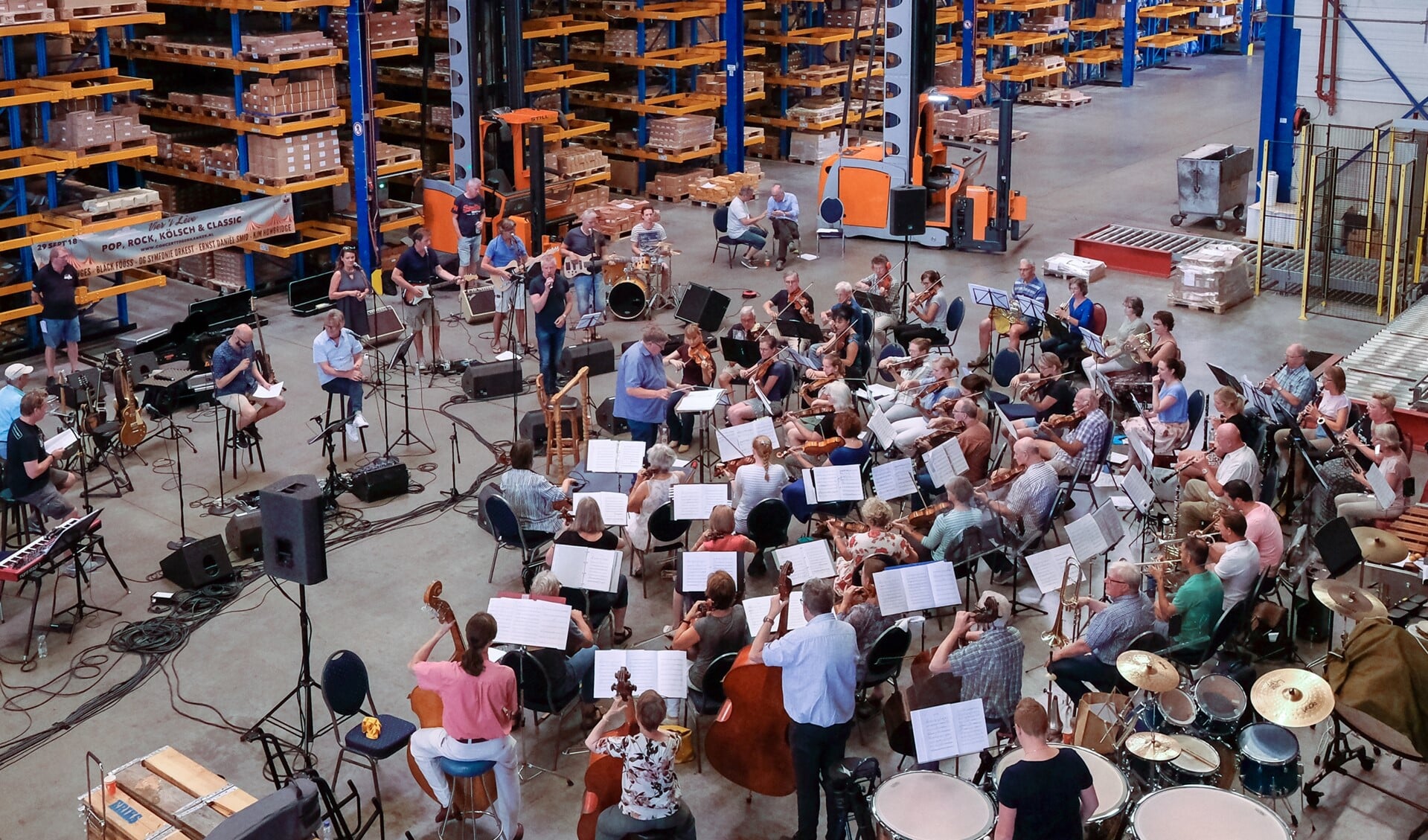 Ruim honderd muzikanten en zangers repeteren in het magazijn van Eurobolt. Foto: Burry van den Brink