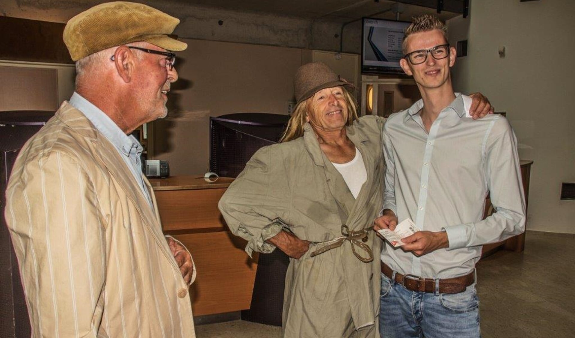 Frans Velthuis en Rob van Druten bieden wethouder Mathijs ten Broeke een kaartje aan voor cabaretvoorstelling 'Heit al geheurt'. Foto: PR