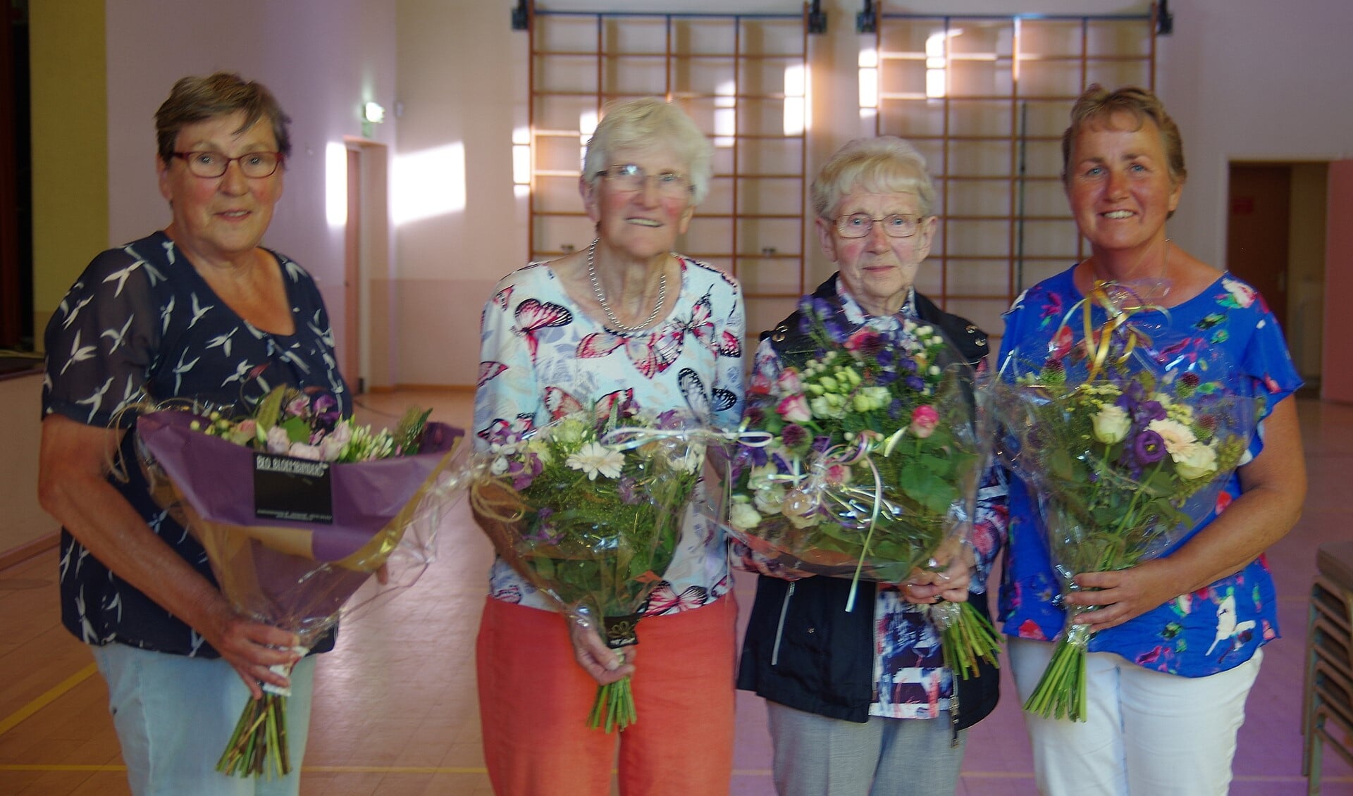 Diny Klompenhouwer, in de bloemetjes gezet vanwege haar grote verdiensten voor de zangvereniging, met naast  de jubilarissen Willey Weenink en Sien Beernink, dirigente Riet Lieverdink (vlnr). Foto: G. W. Huinink