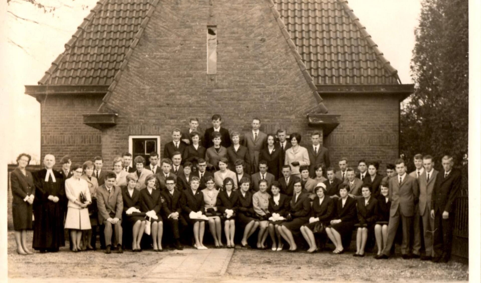 De belijdeniscatechisanten uit 1966 voor de voormalige pastorie aan de Domineesteeg met onder meer dominee Barnard .Foto: PR.  