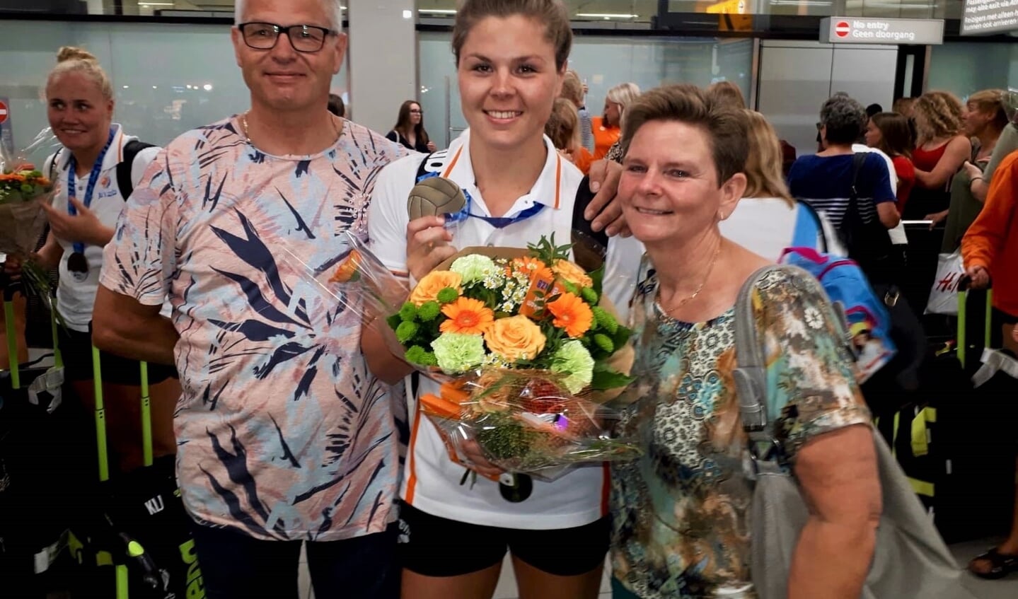 Vivian met medaille te midden van haar ouders, Leo en Miranda Sevenich, na aankomst op Schiphol.