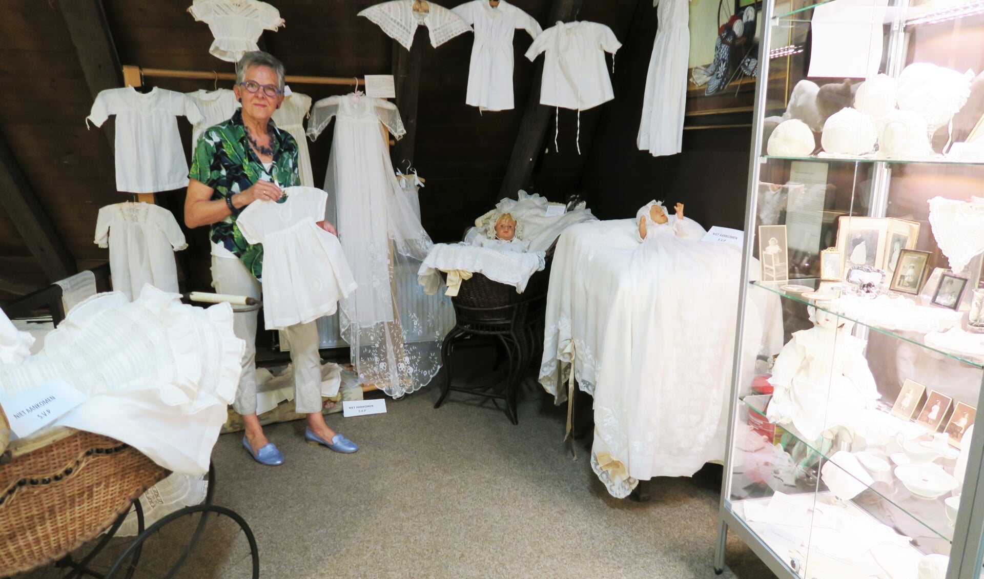 Nancy Corts-Stunnenberg te midden van haar expositie, bestaande uit voornamelijk babykleding van weleer. Foto: Theo Huijskes