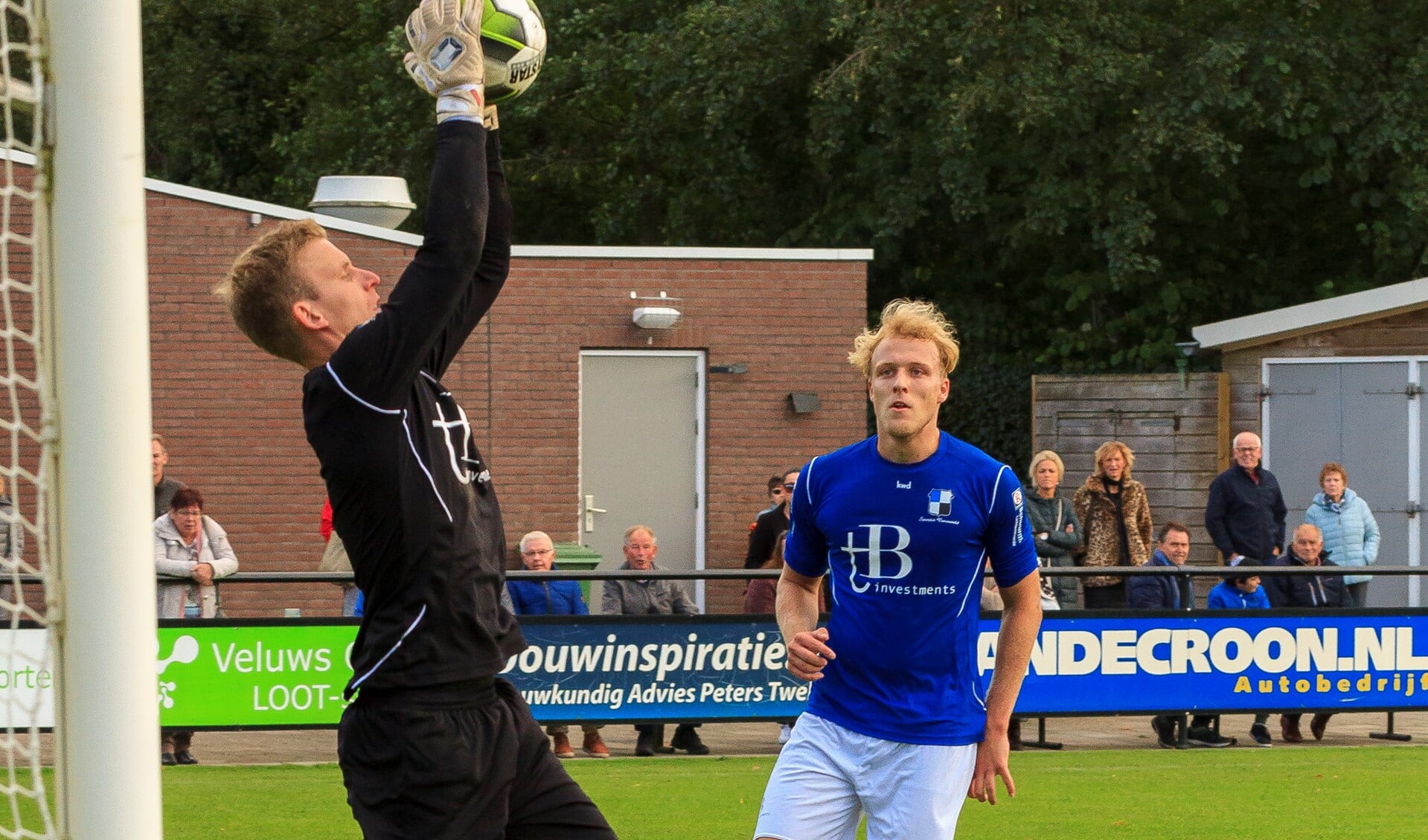 Lucas Breukelaar kijkt toe hoe Varsseveld-doelman Joost Riewald de bal uit de lucht plukt.  Foto: Henk Kok/Voorwaarts Twello
