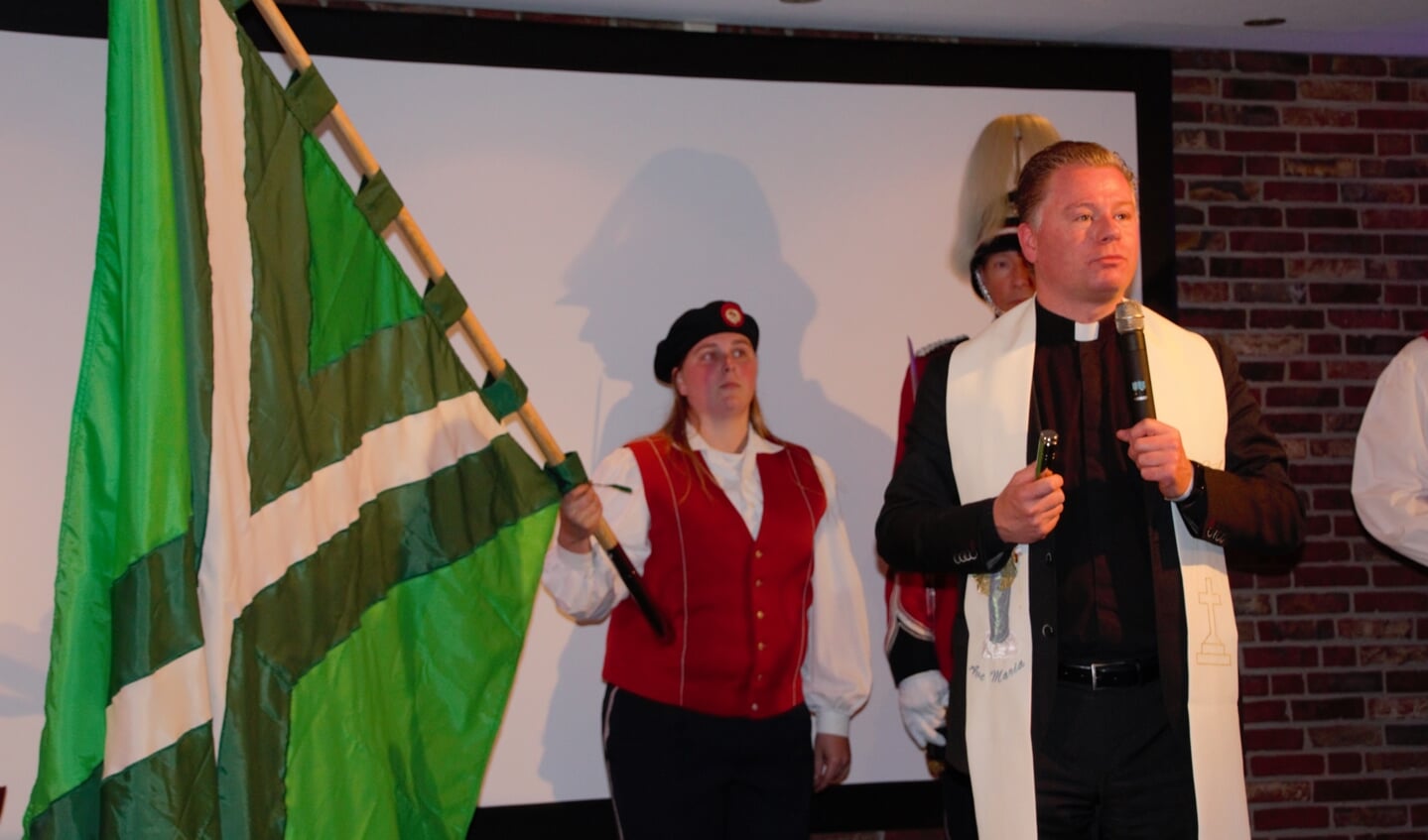 Kyra Stortelaar presenteert het vaandel voor de inzegening door pastoor Den Hartog. Foto: Annekée Cuppers