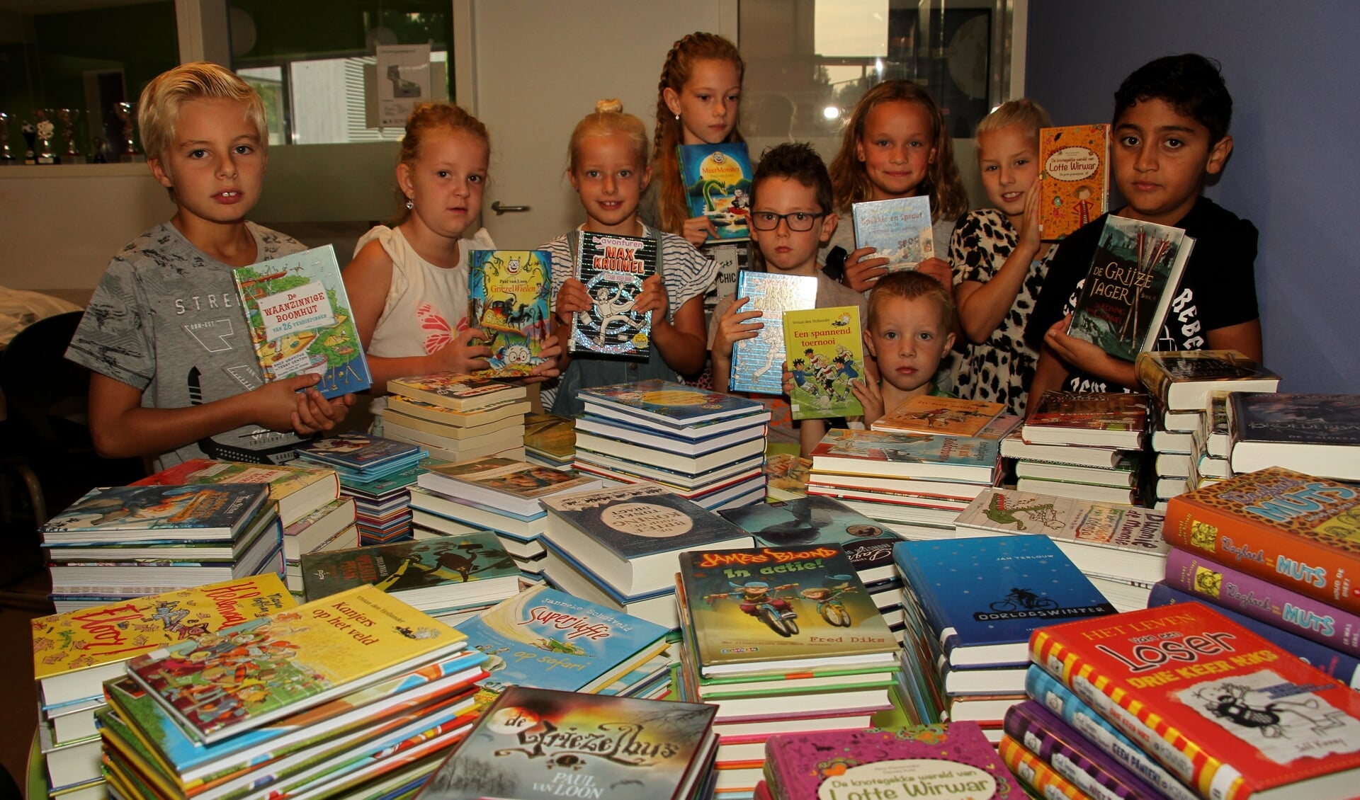 Bonne, Julijn, Sarah, Maud, Nick, Thijs, Jasmijn, Nina en Ghabriël kijken naar de stapels boeken. Foto: Liesbeth Spaansen
