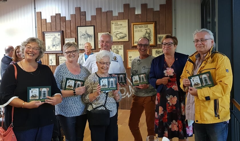 Irmgard Bomers heeft zojuist haar moeder (midden voor) het eerste exemplaar overhandigd, staand tussen hen die op hun manier een band met het pand hebben. Foto: Henri Walterbos