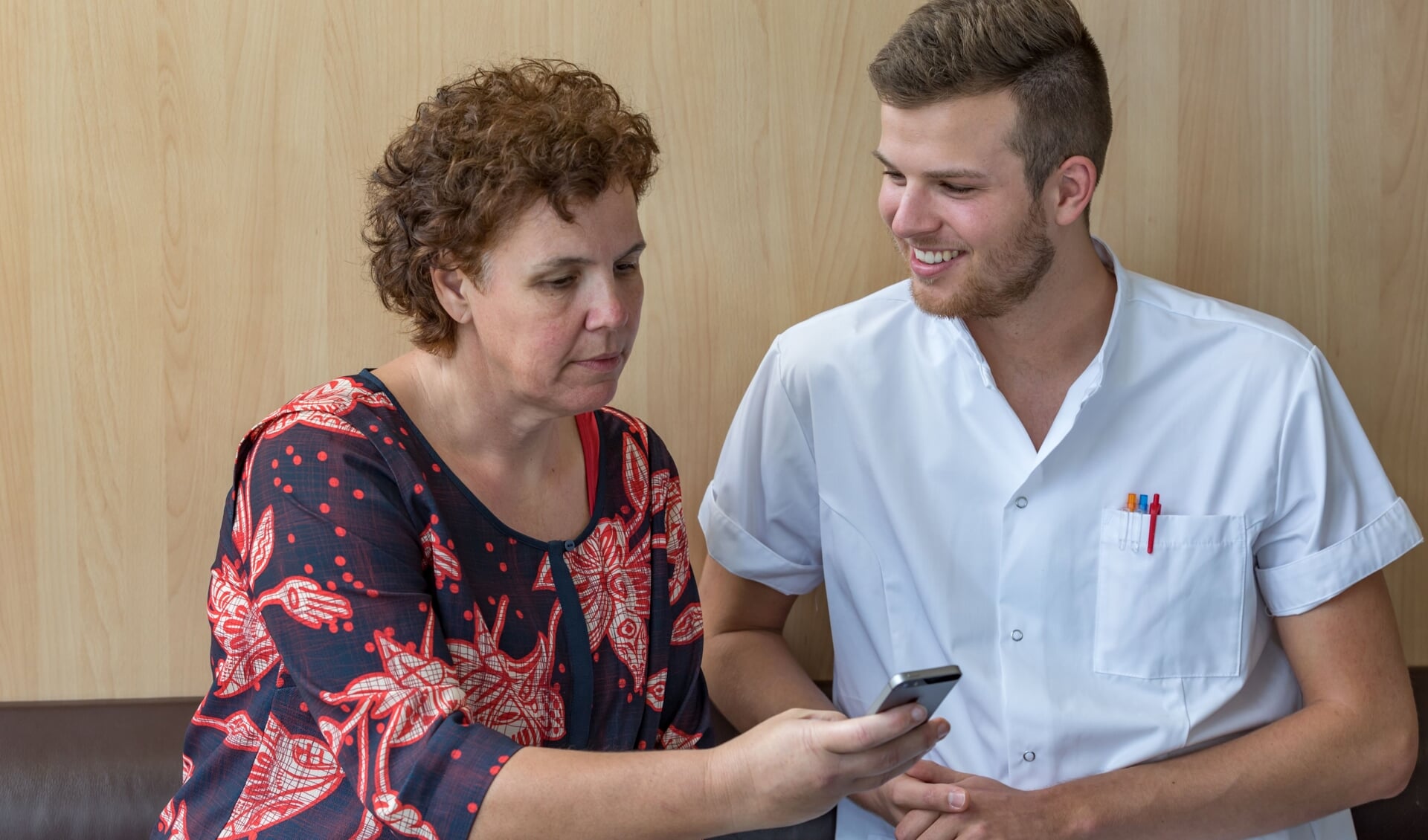 Zorgverlener geeft patiënt instructie over BeterDichtbij app. Foto: PR