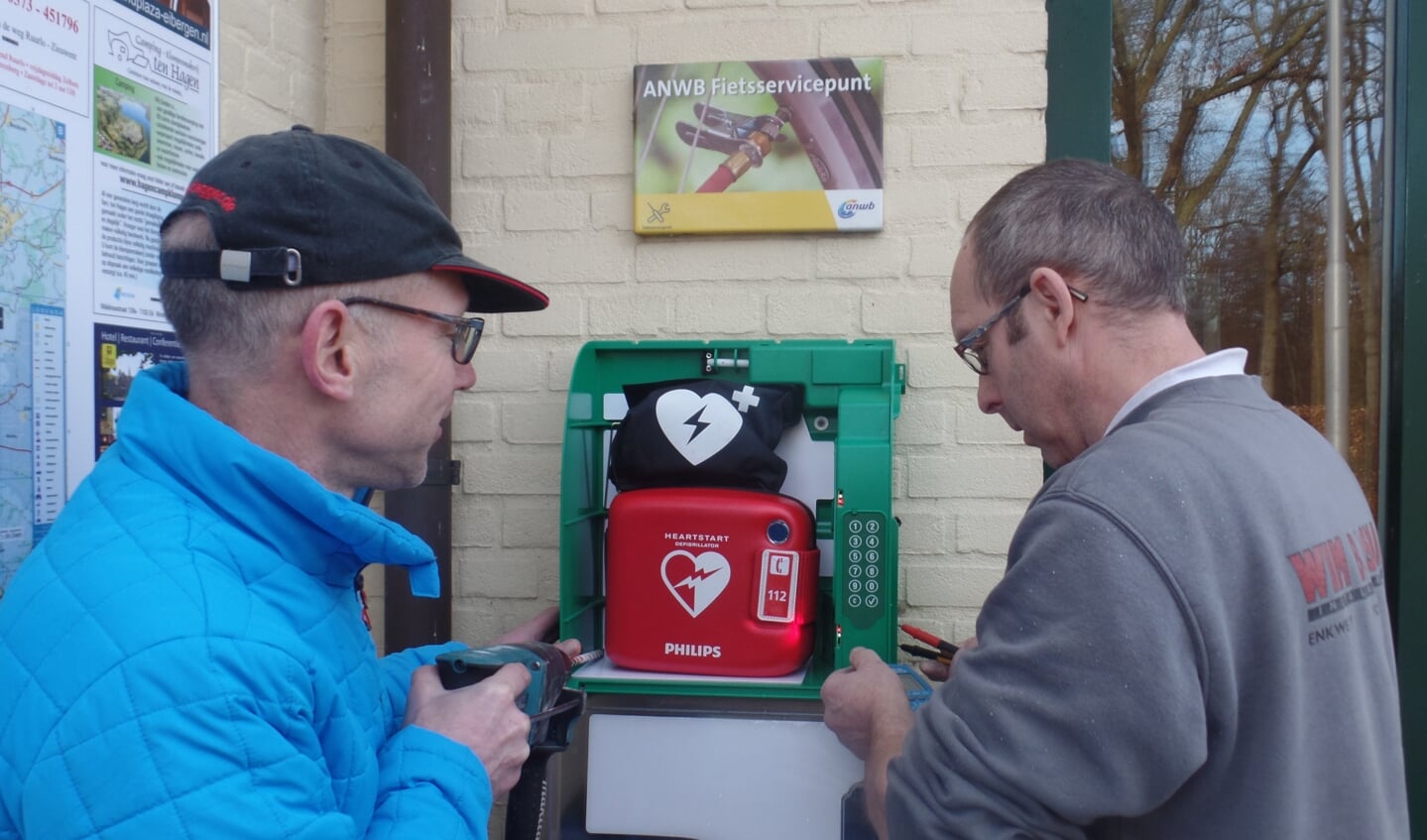 Gerrit Otten (l) en Reinold Haaring bevestigden zaterdag de nieuwe AED aan de muur bij 't Wapen van 't Medler. Foto: Jan Hendriksen