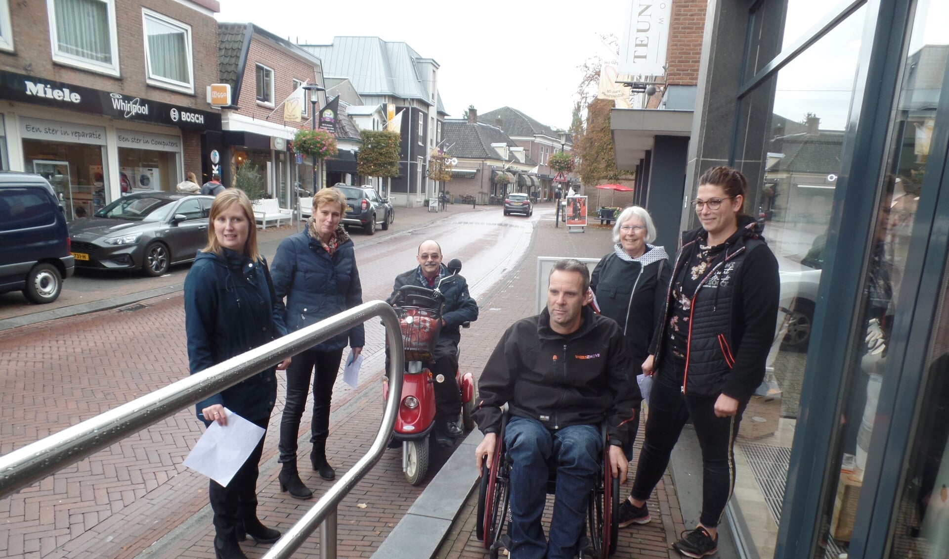 Rudi van de Esschert (rolstoel) en Wil Paulis (scootmobiel) testen onder toeziend oog van onder meer Marieke Heusinkveld en Alianne Koning de toegankelijkheid van de ondernemingen. Foto: Jan Hendriksen
