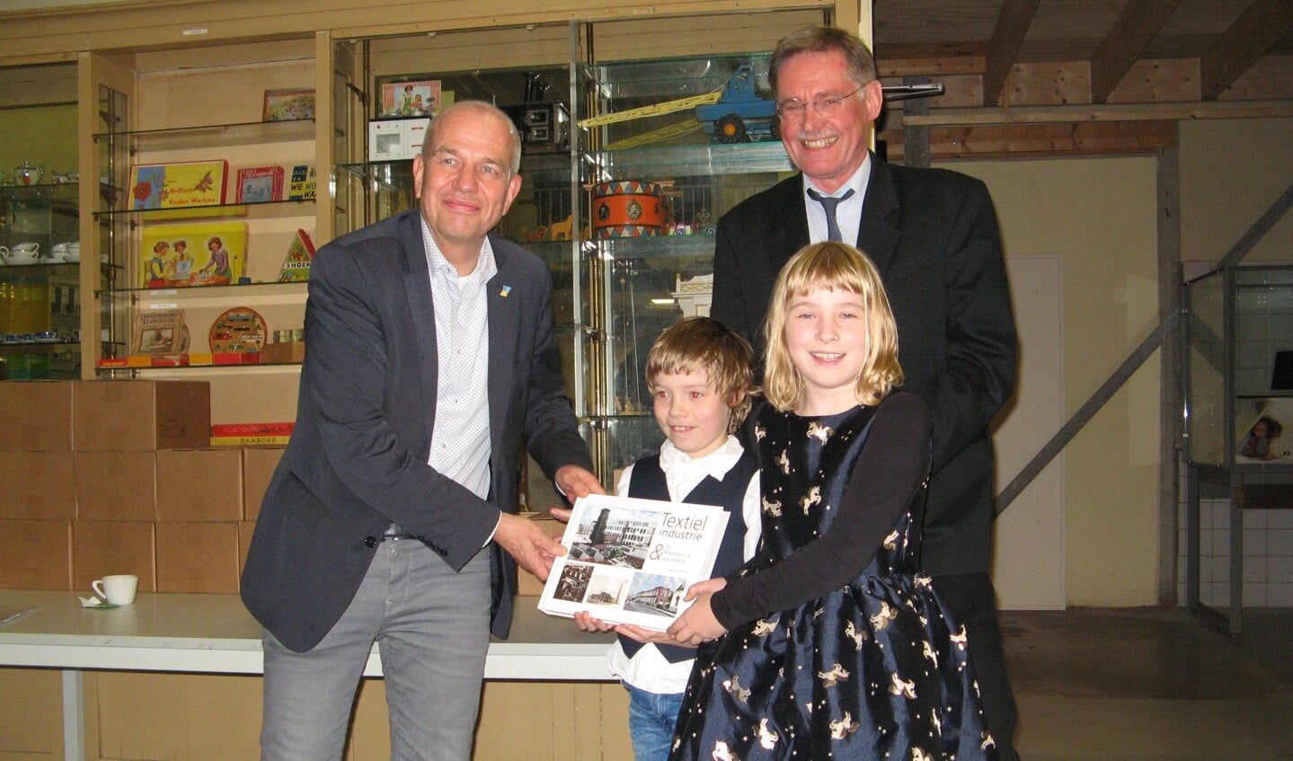 Arjan Ligtenbarg en zijn kinderen Aidrian en Wencke overhandigen het eerste exemplaar van 'Textielindustrie in Winterswijk & omstreken'' aan wethouder Wim Aalderink. Foto: Bart Kraan