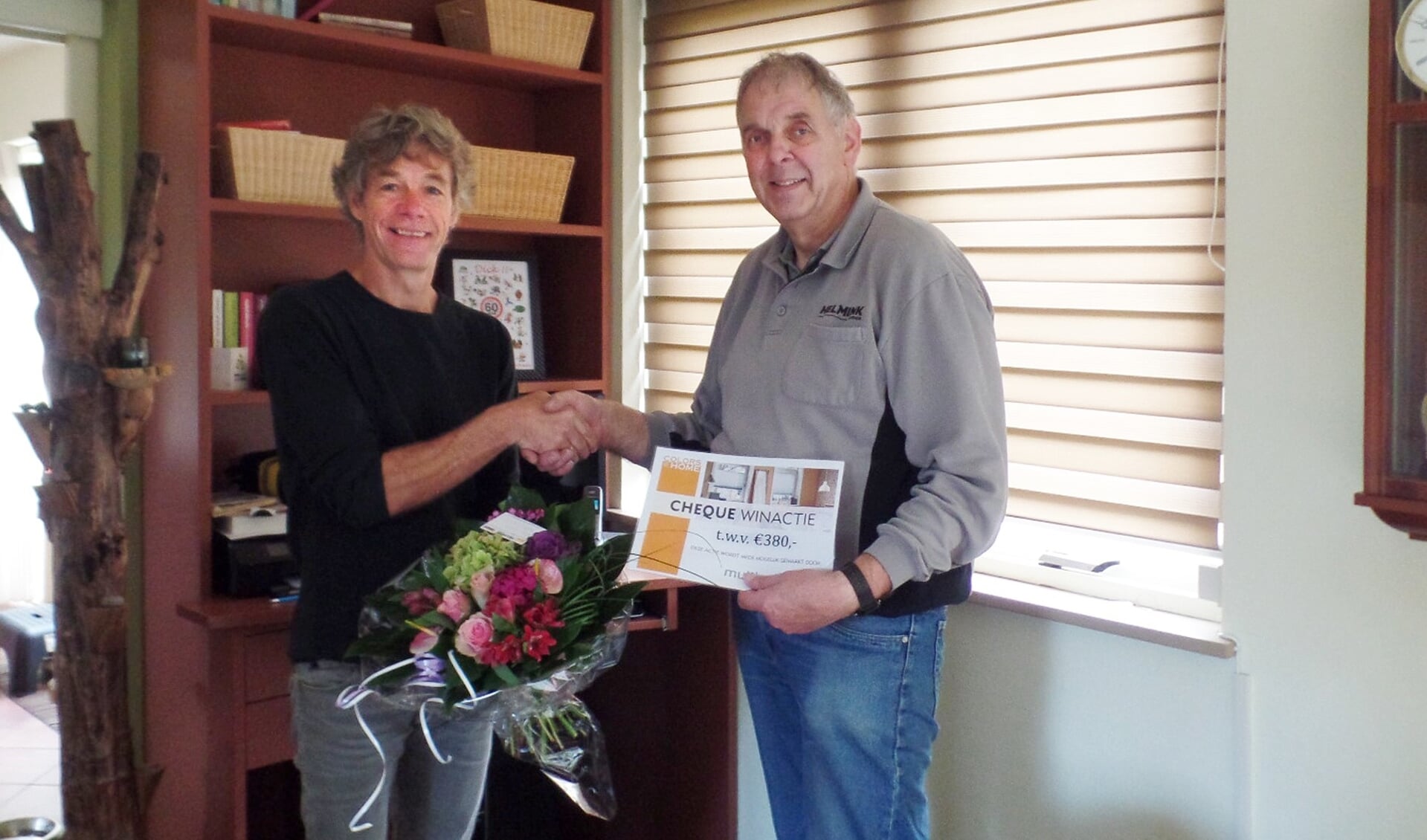 Bernard Helmink reikt de symbolische cheque en een boeket bloemen uit aan Dick Knoef. Foto: PR