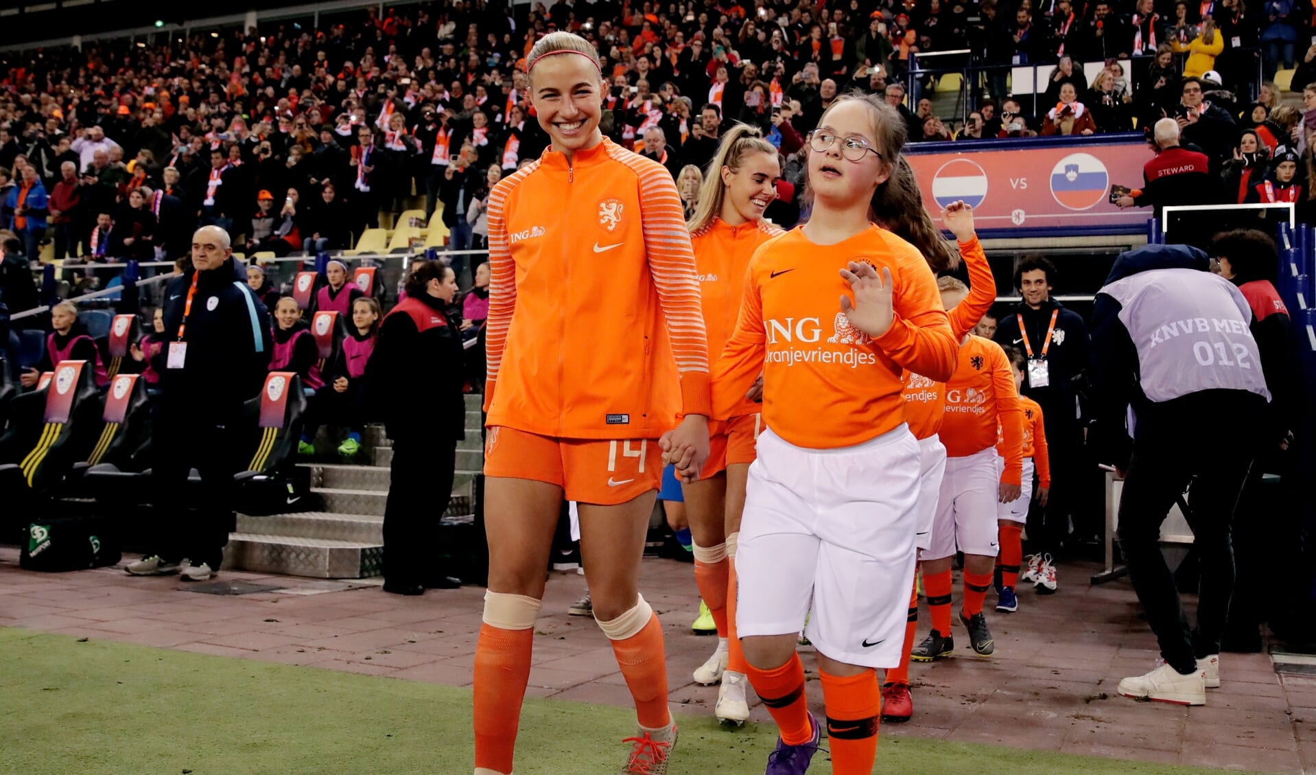 Voetbalster Jikke begeleidt de OranjeLeeuwinnen het veld op. Foto: PR