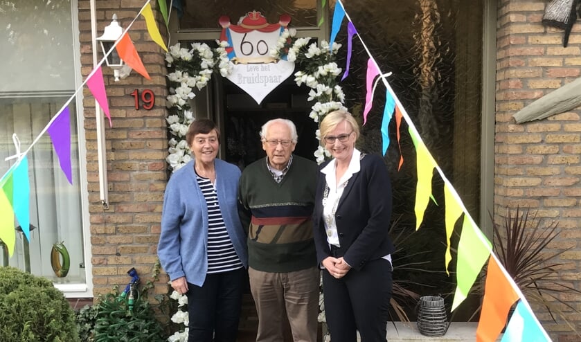 Derry en Gerrit Ridder samen met burgemeester Marianne Besselink bij hun versierde woning. Foto: PR.