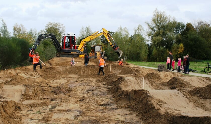Kinderen kijken toe hoe de fietscrossbaan wordt aangelegd. Foto: Dinès Quist