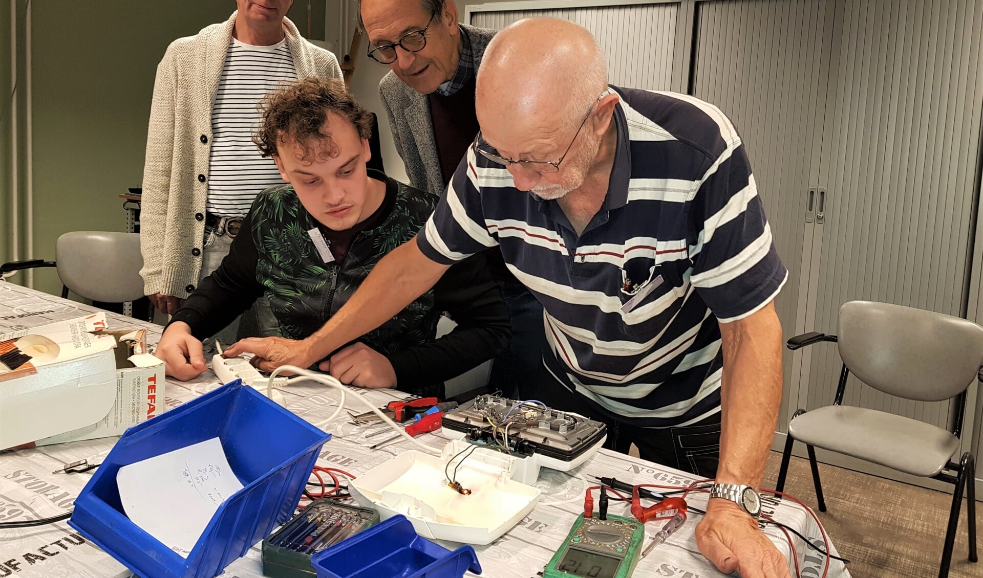 Vincent Raben (rechts) en Timon Nijman bezig met een tosti-ijzer, gadegeslagen door René Penterman (links) en Henk Schut.