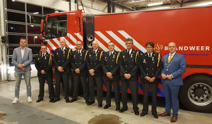Postcommandant Roland Lieverdink (l) en burgemeester Joris Bengevoord flankeren de zeven gedecoreerden. Foto: Han van de Laar